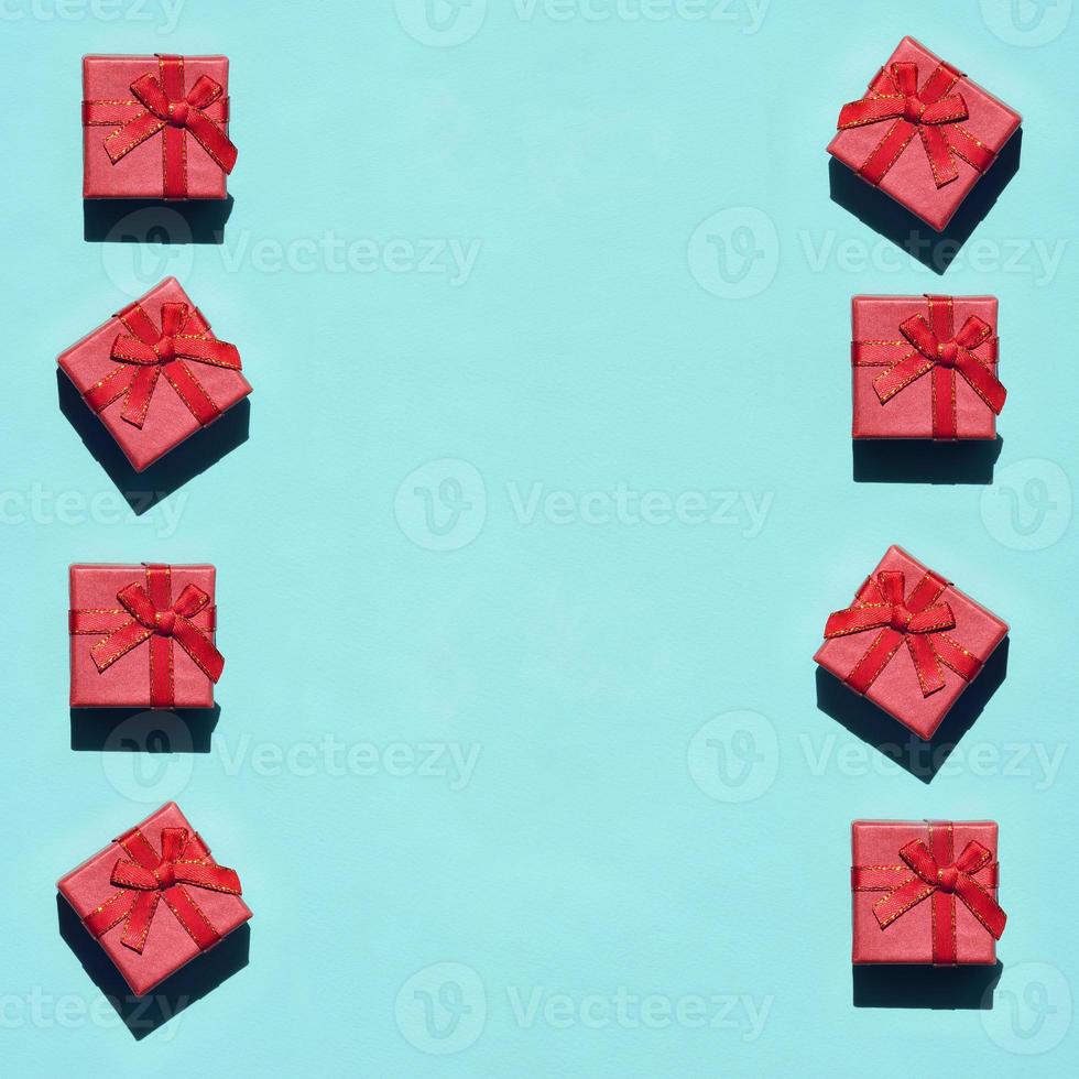 Many small red pink gift boxes on texture background of fashion trendy pastel blue color paper in minimal concept. Abstract pattern photo