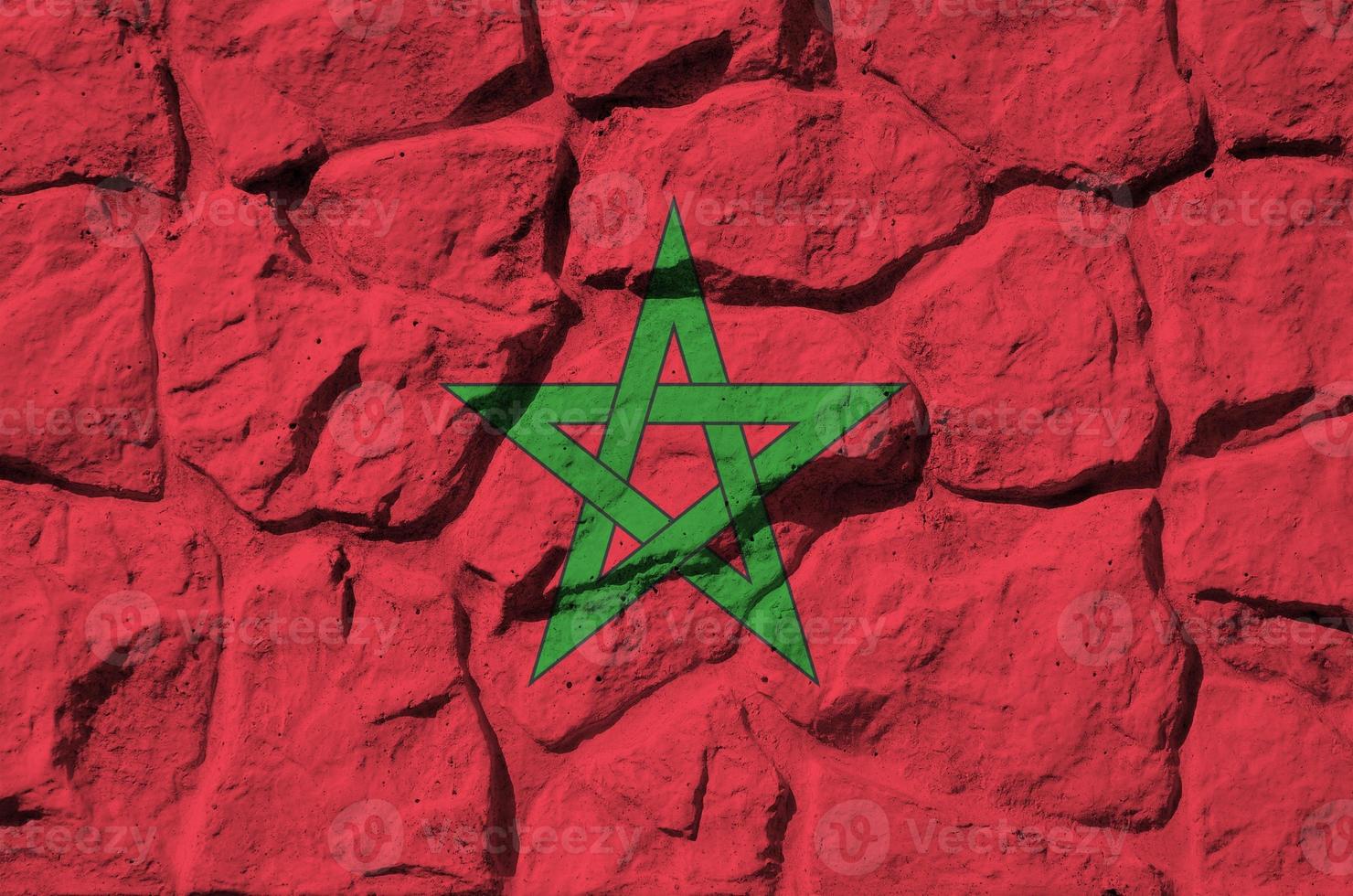 Morocco flag depicted in paint colors on old stone wall closeup. Textured banner on rock wall background photo