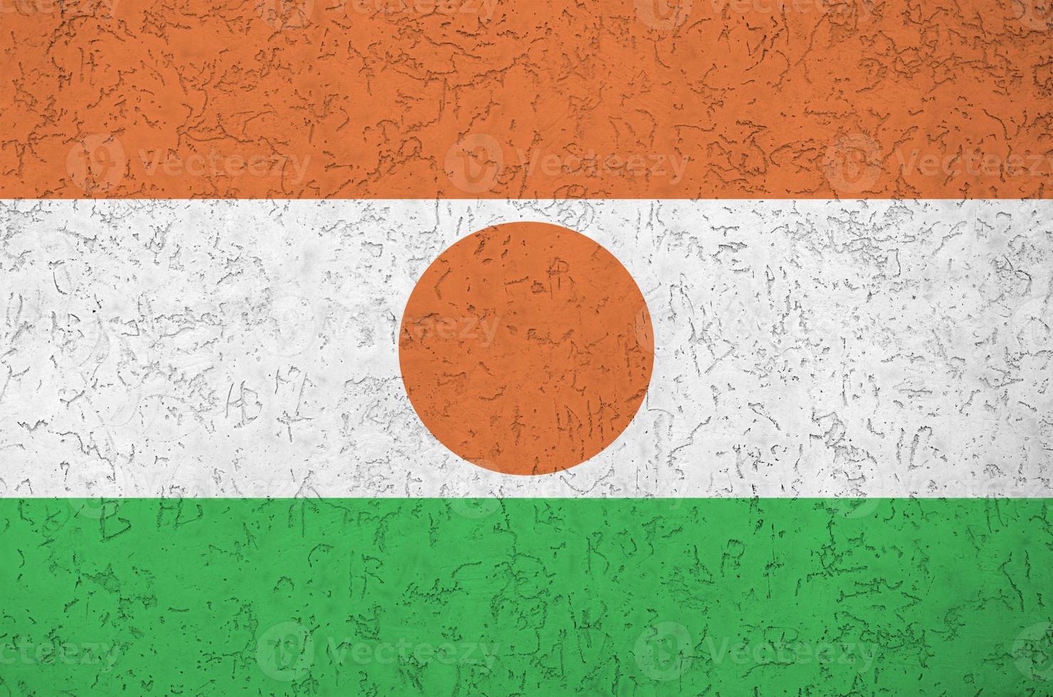 Niger flag depicted in bright paint colors on old relief plastering wall. Textured banner on rough background photo