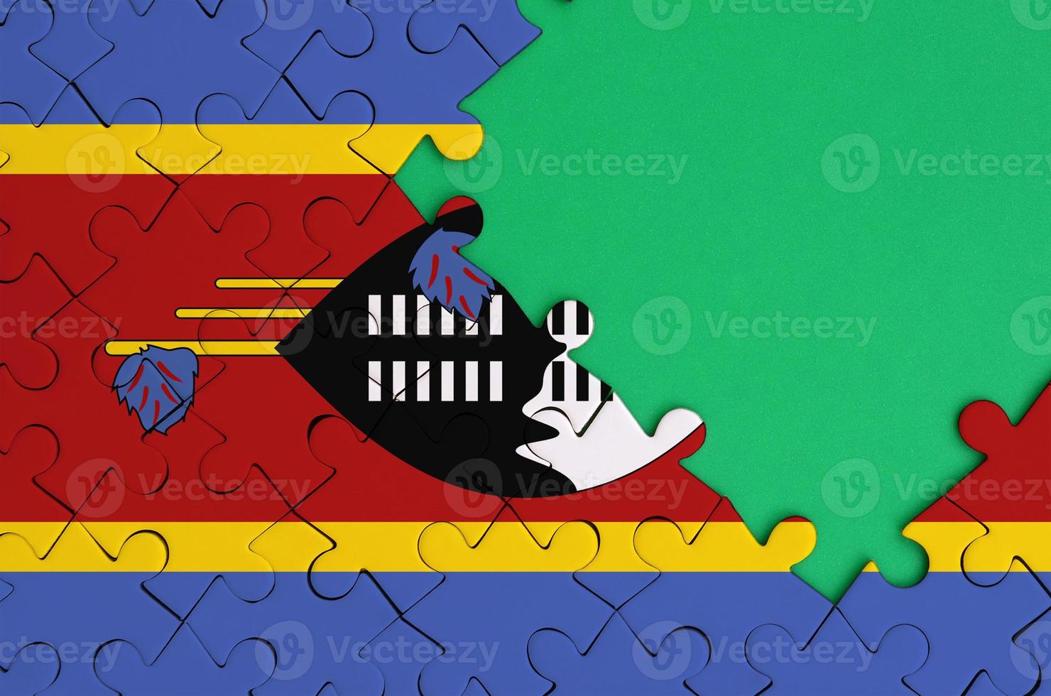 Swaziland flag  is depicted on a completed jigsaw puzzle with free green copy space on the right side photo