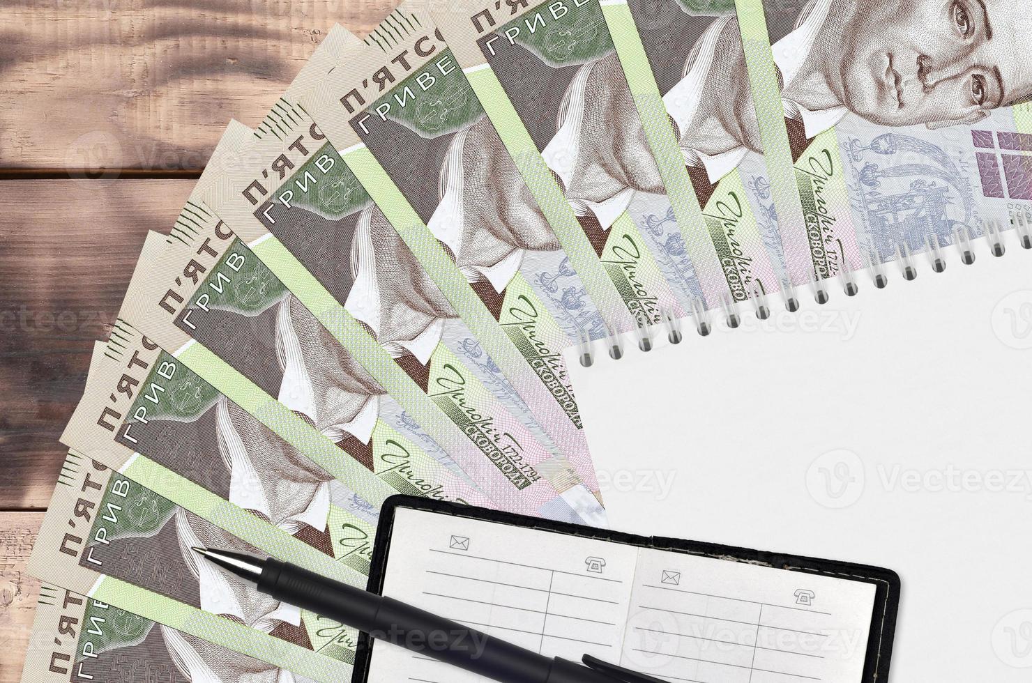 500 Ukrainian hryvnias bills fan and notepad with contact book and black pen. Concept of financial planning and business strategy photo