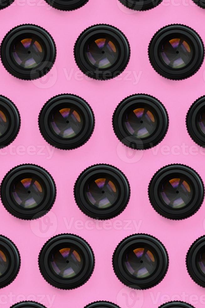 A few camera lenses with a closed aperture lie on texture background of fashion pastel pink color paper in minimal concept. Abstract trendy pattern photo