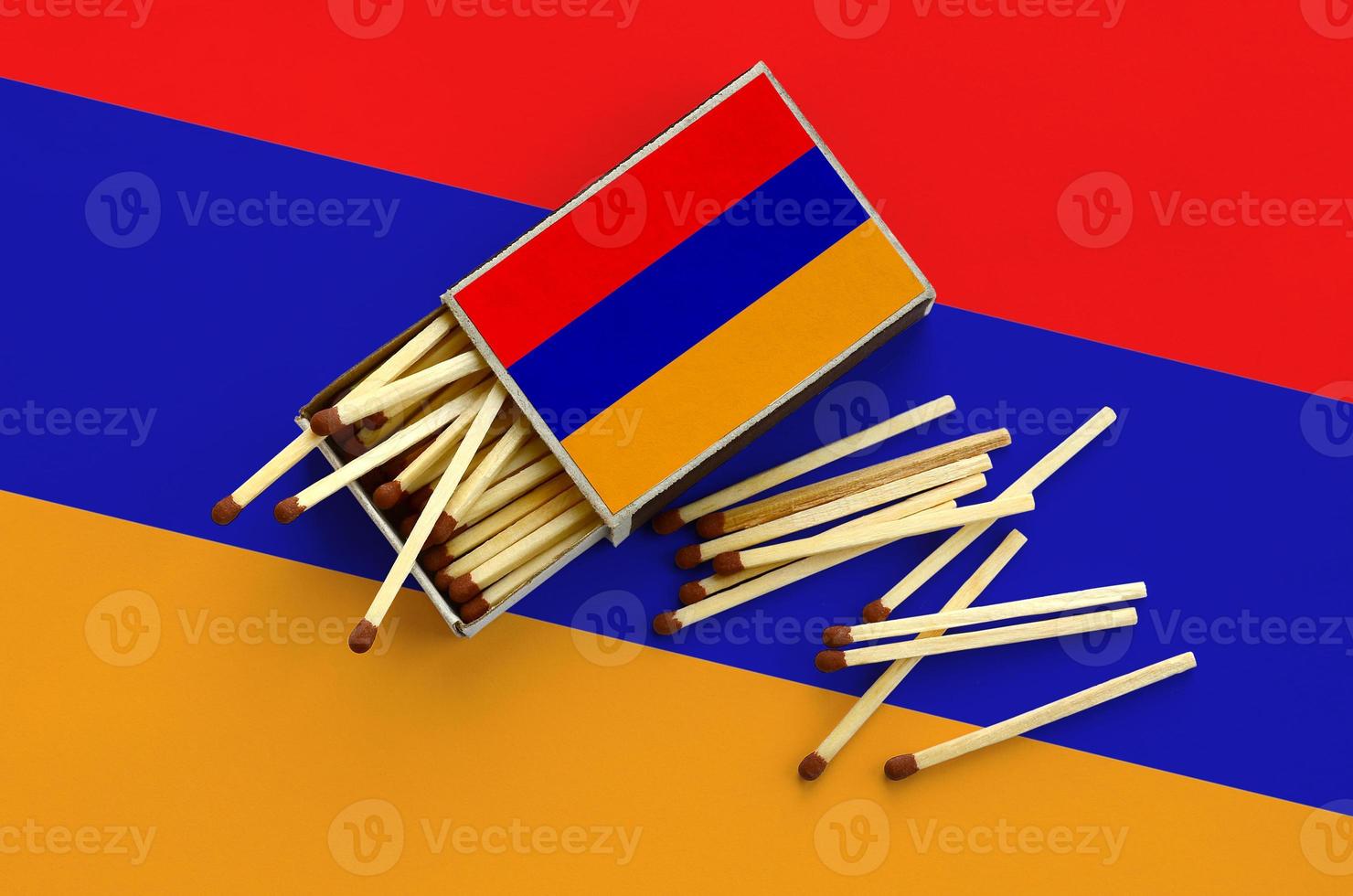 Armenia flag  is shown on an open matchbox, from which several matches fall and lies on a large flag photo
