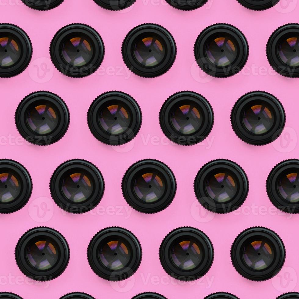A few camera lenses with a closed aperture lie on texture background of fashion pastel pink color paper in minimal concept. Abstract trendy pattern photo