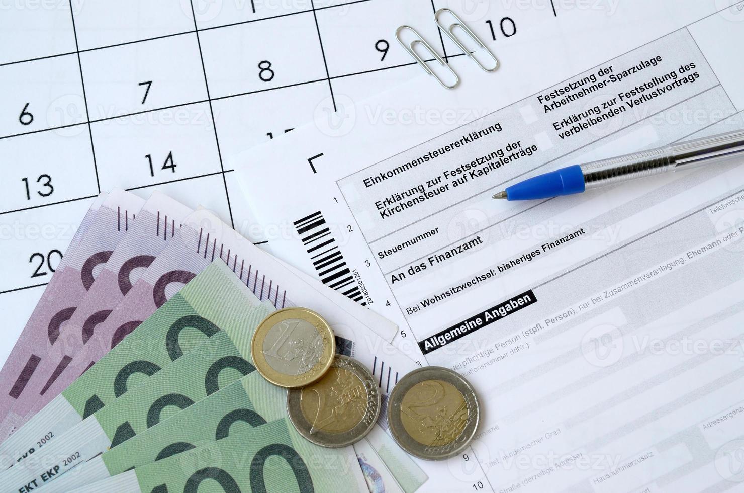 el formulario de impuestos alemán con bolígrafo y billetes de dinero europeos se encuentra en el calendario de la oficina. contribuyentes en alemania que usan la moneda euro para pagar impuestos foto