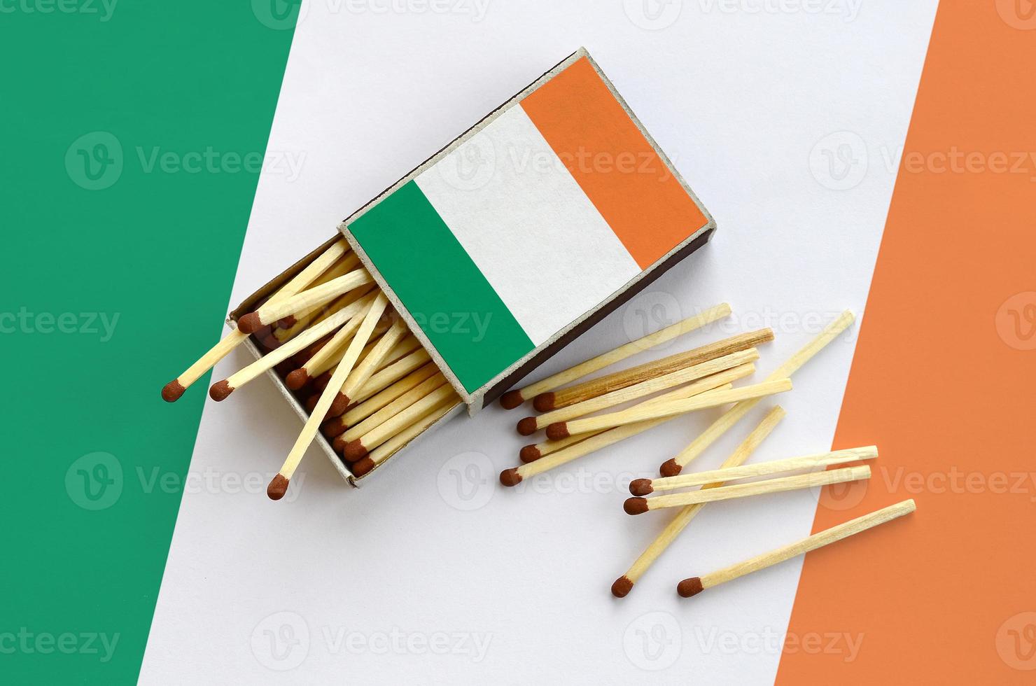 Ireland flag  is shown on an open matchbox, from which several matches fall and lies on a large flag photo