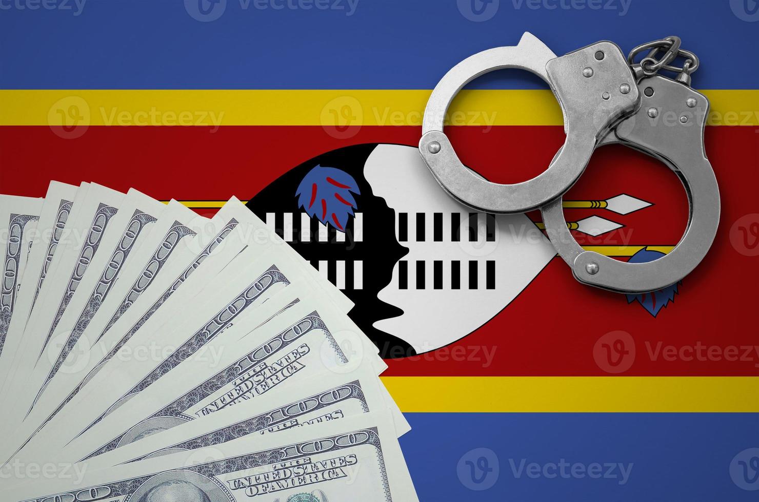 Swaziland flag  with handcuffs and a bundle of dollars. The concept of illegal banking operations in US currency photo
