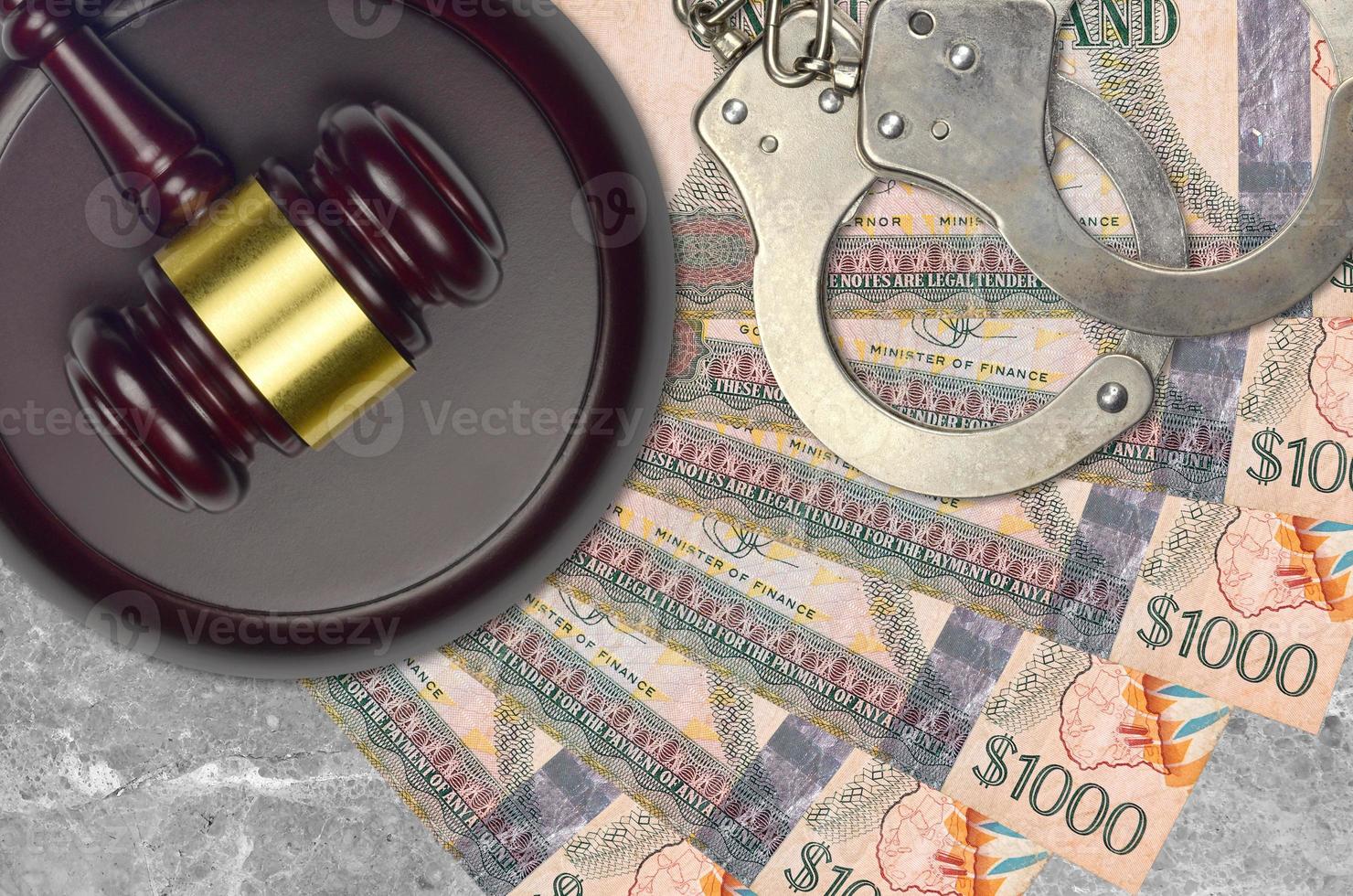 1000 Guyanese dollars bills and judge hammer with police handcuffs on court desk. Concept of judicial trial or bribery. Tax avoidance photo