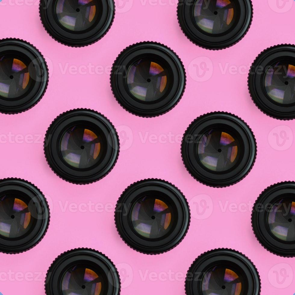 A few camera lenses with a closed aperture lie on texture background of fashion pastel pink color paper in minimal concept. Abstract trendy pattern photo