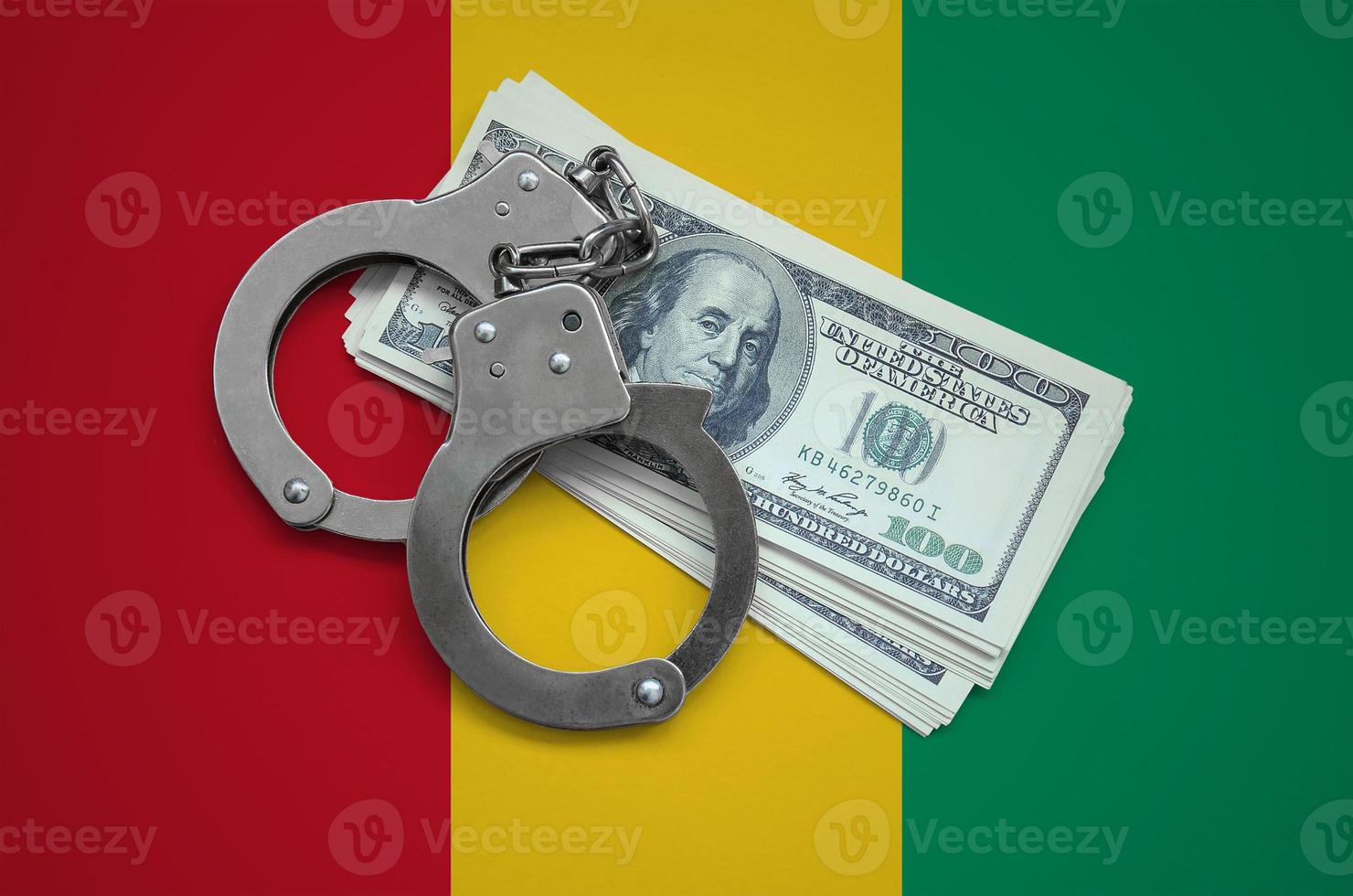 Guinea flag  with handcuffs and a bundle of dollars. Currency corruption in the country. Financial crimes photo