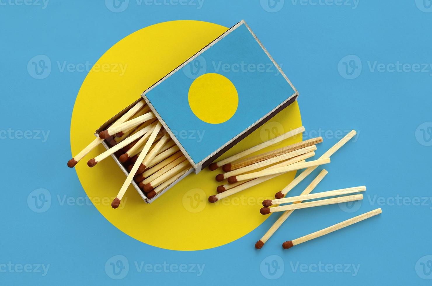 Palau flag  is shown on an open matchbox, from which several matches fall and lies on a large flag photo