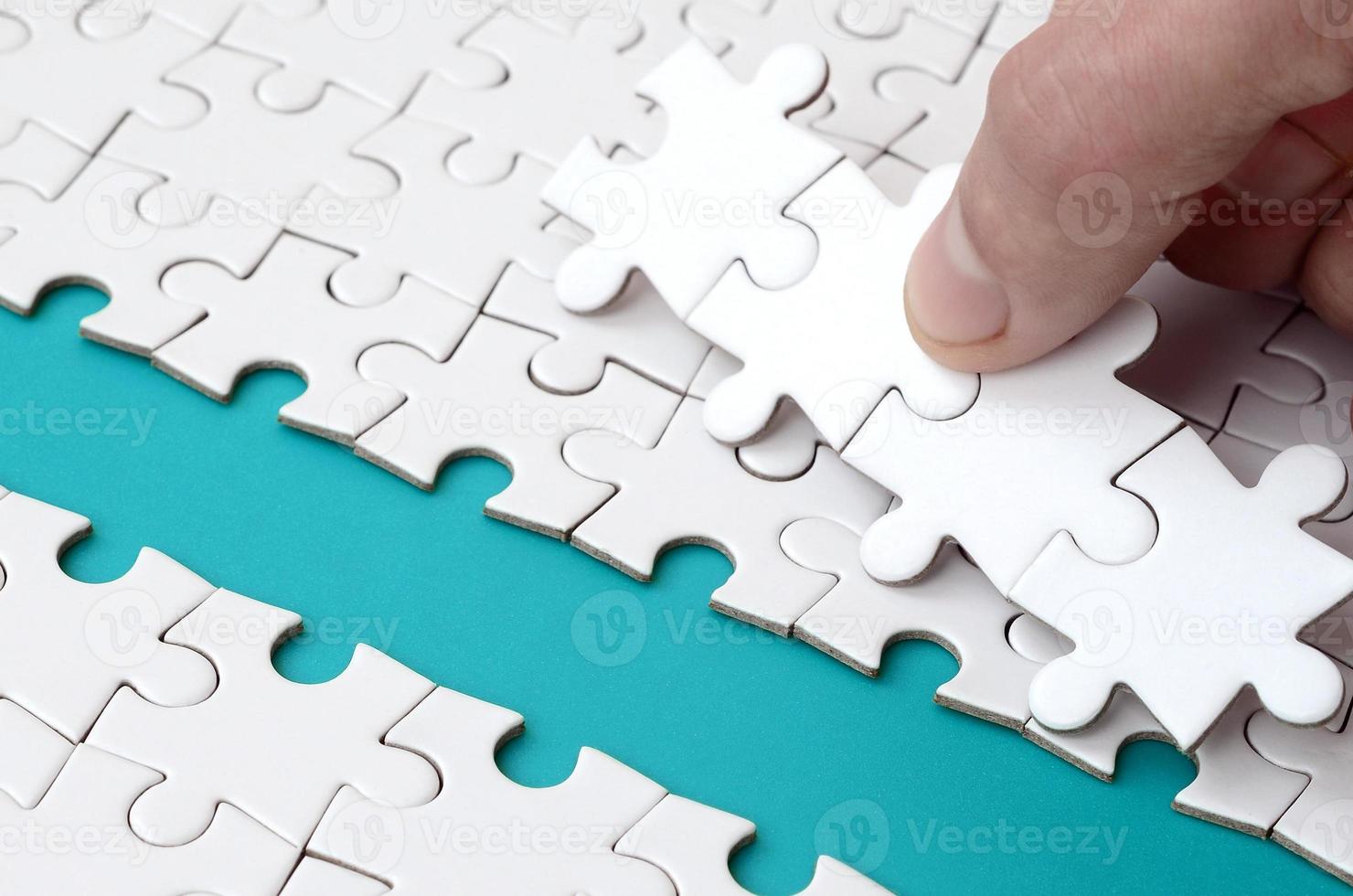 The human hand paves the way to the surface of the jigsaw puzzle, forming a blue space. The concept of overcoming the difficulties on the way to success photo