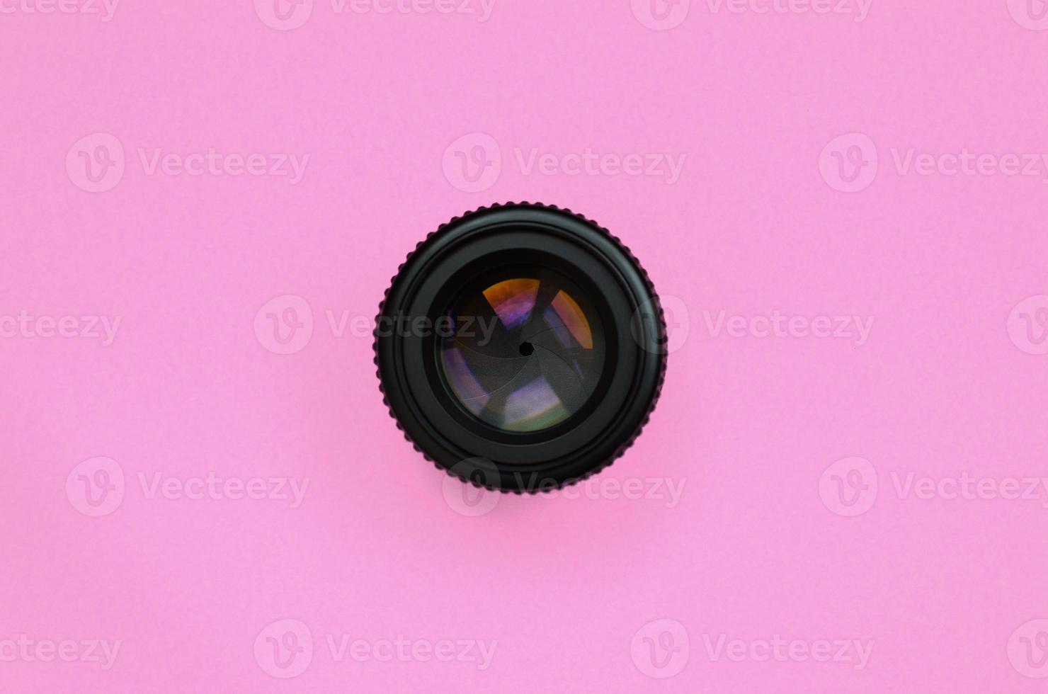Camera lens with a closed aperture lie on texture background of fashion pastel pink color paper in minimal concept photo