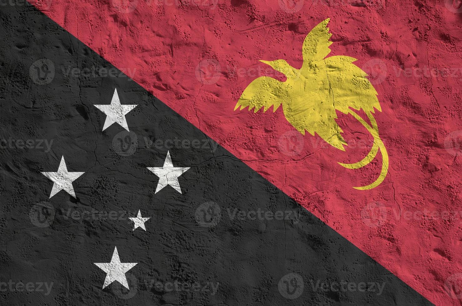 Papua New Guinea flag depicted in bright paint colors on old relief plastering wall. Textured banner on rough background photo