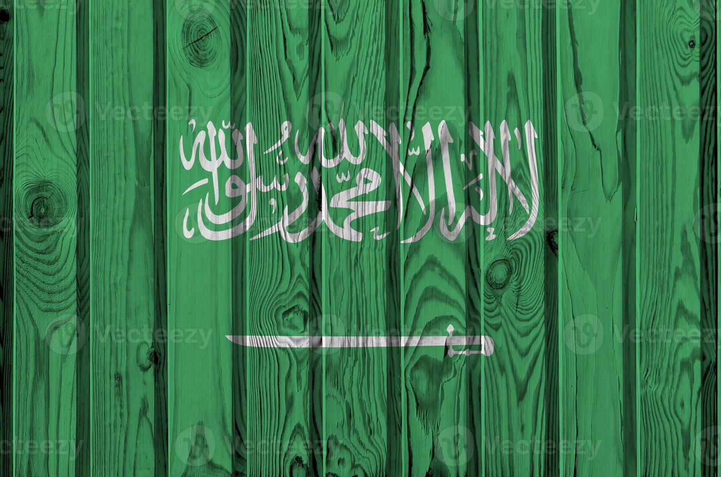 Saudi Arabia flag depicted in bright paint colors on old wooden wall. Textured banner on rough background photo