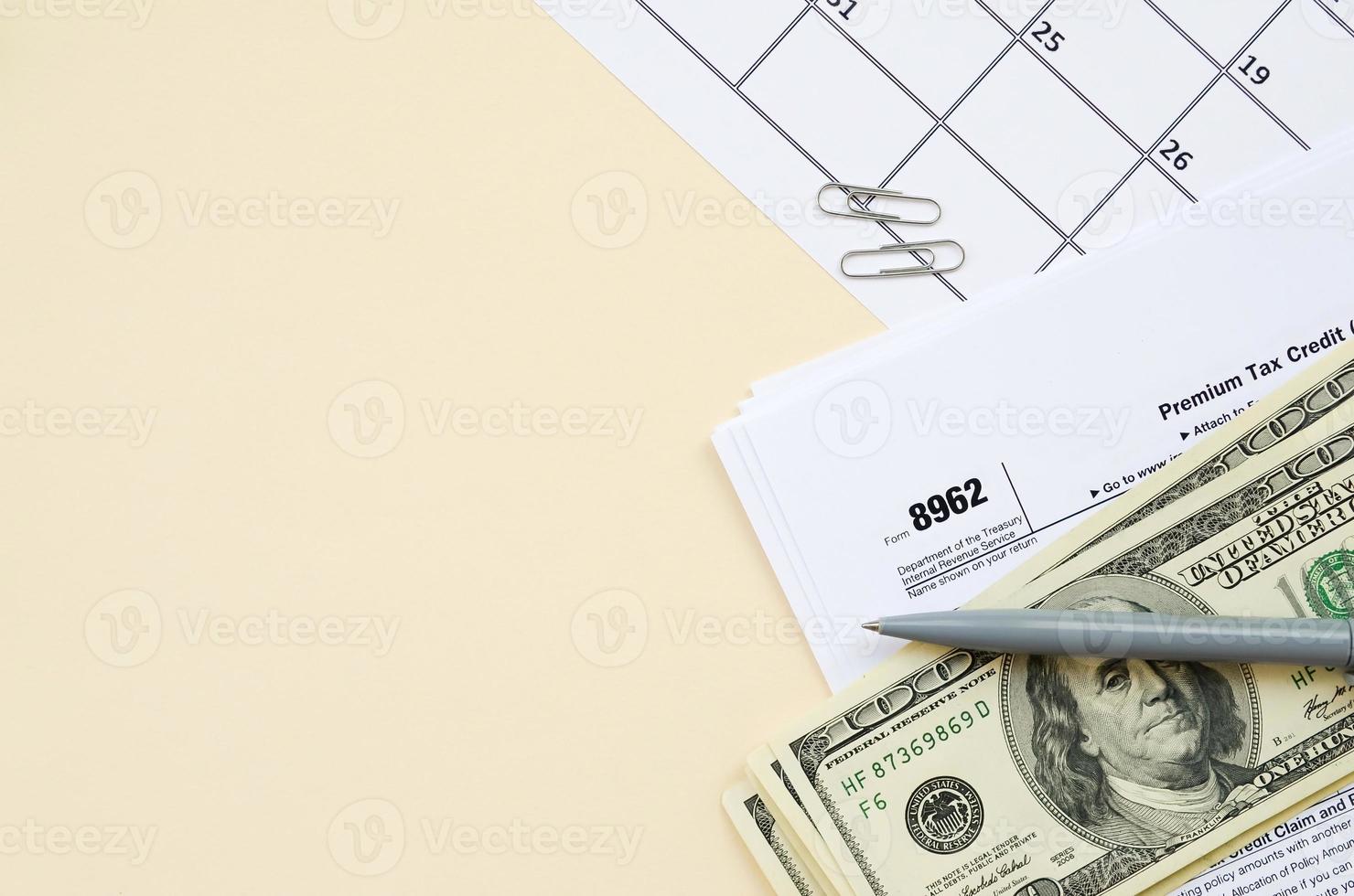 IRS Form 8962 Premium tax cerdit PTC blank lies with pen and many hundred dollar bills on calendar page photo