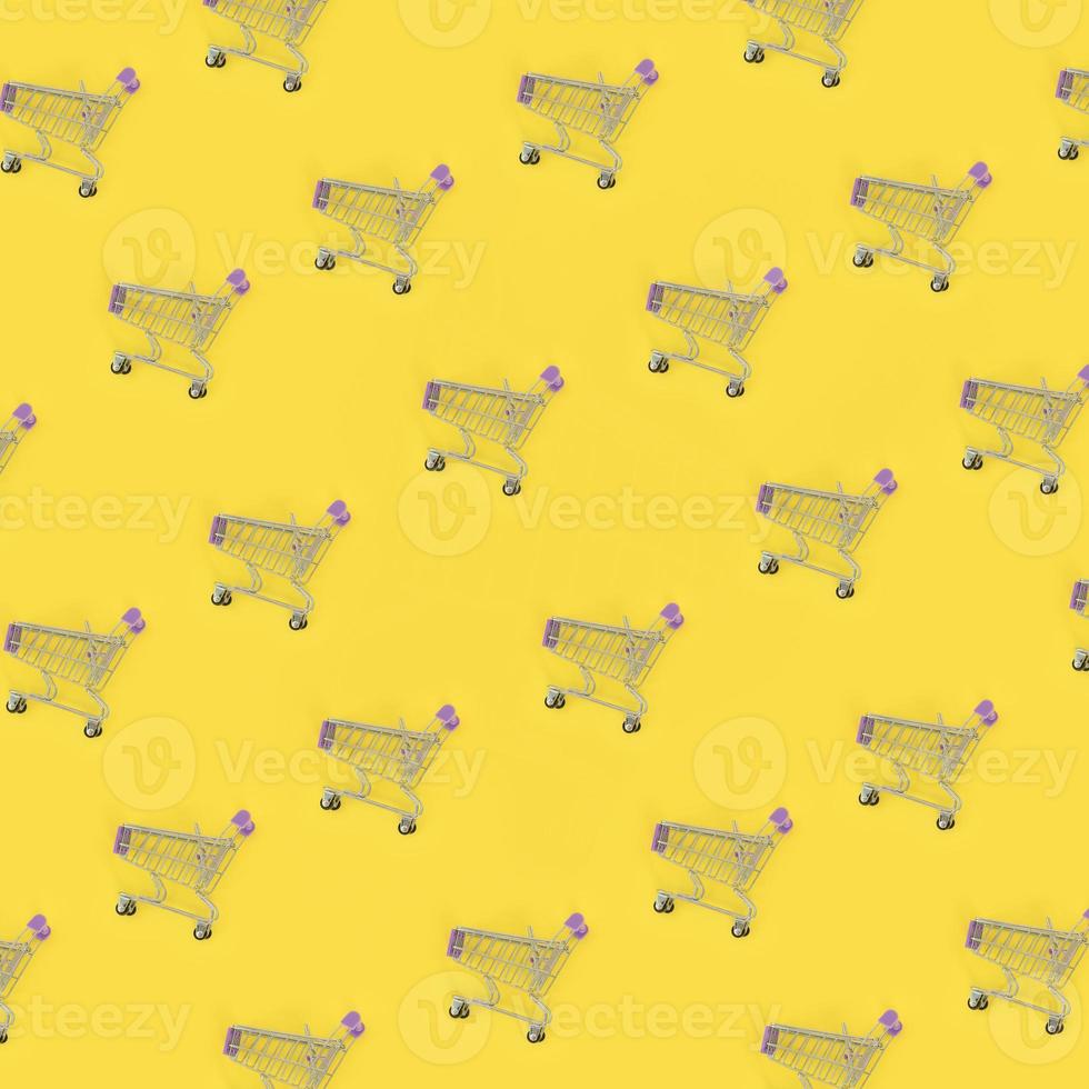 Shopping addiction, shopping lover or shopaholic concept. Many small empty shopping carts perform a pattern on a pastel colored paper background. Flat lay composition, top view photo