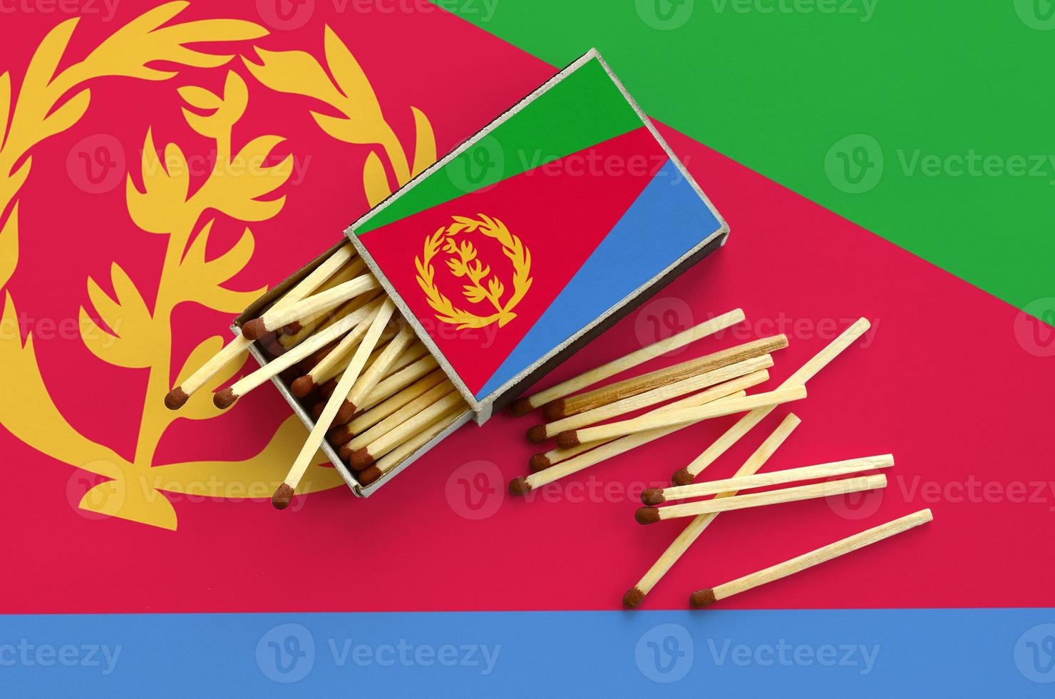 Eritrea flag  is shown on an open matchbox, from which several matches fall and lies on a large flag photo