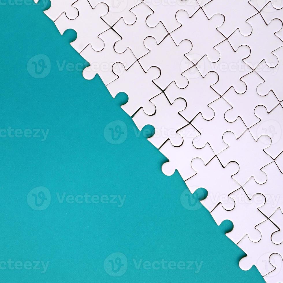 Fragment of a folded white jigsaw puzzle on the background of a blue plastic surface. Texture photo with copy space for text