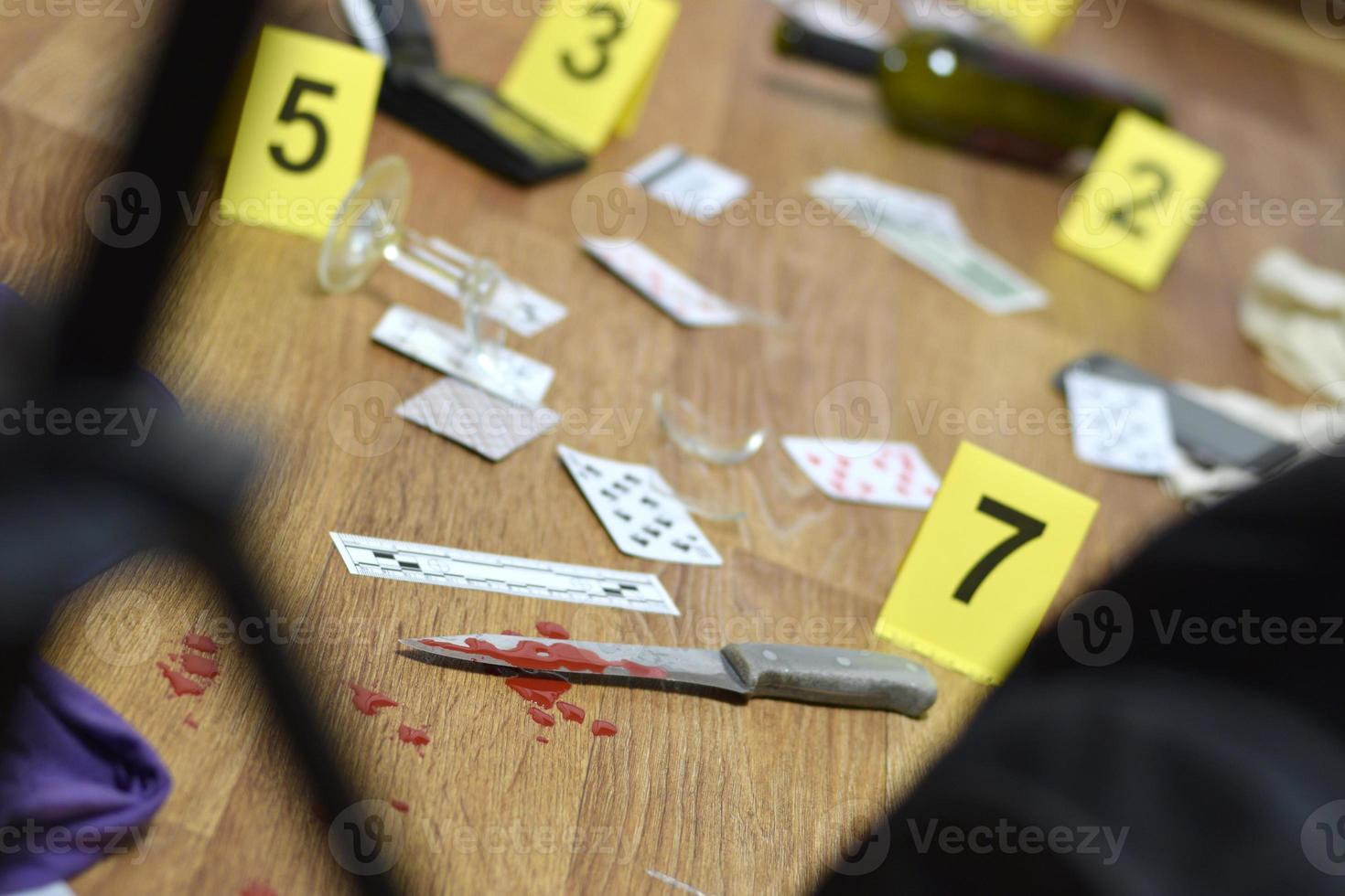 investigación de la escena del crimen - numeración de evidencias después del asesinato en el apartamento. un montón de naipes, billetera y botella de vino como evidencia foto