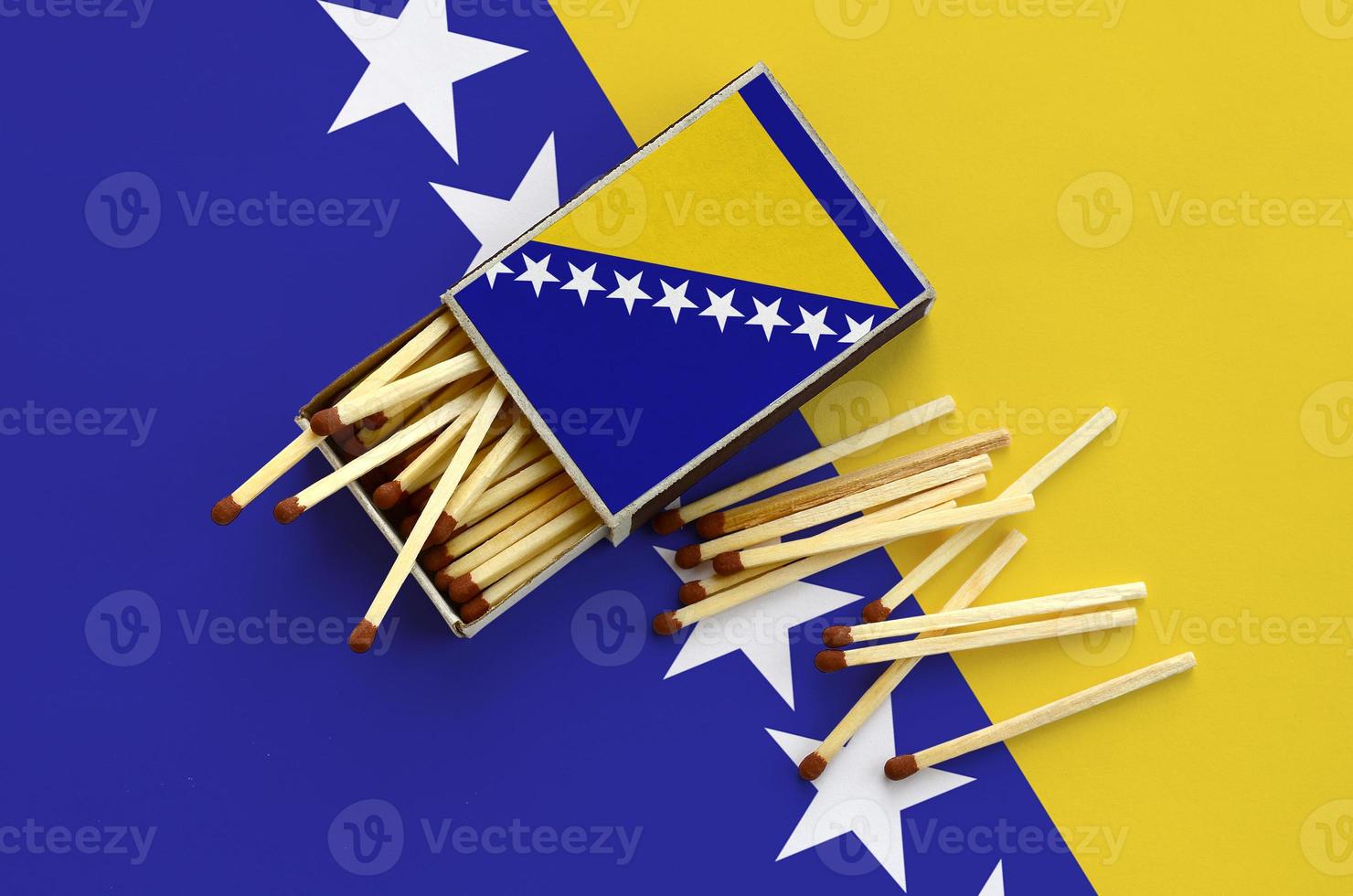 Bosnia and Herzegovina flag  is shown on an open matchbox, from which several matches fall and lies on a large flag photo
