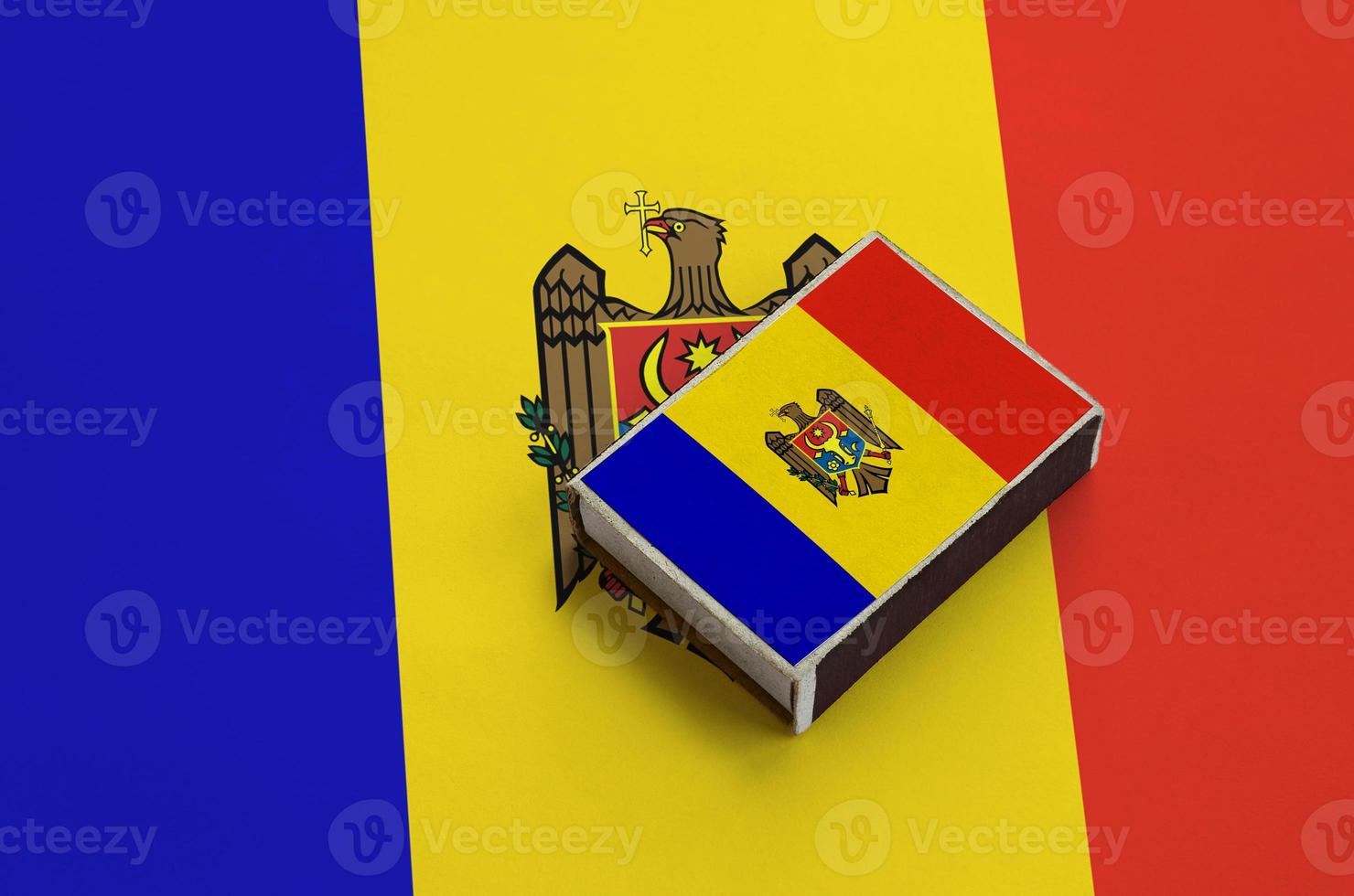 Moldova flag  is pictured on a matchbox that lies on a large flag photo