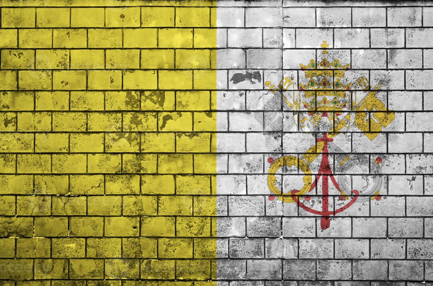 la bandera del estado de la ciudad del vaticano está pintada en una vieja pared de ladrillos foto