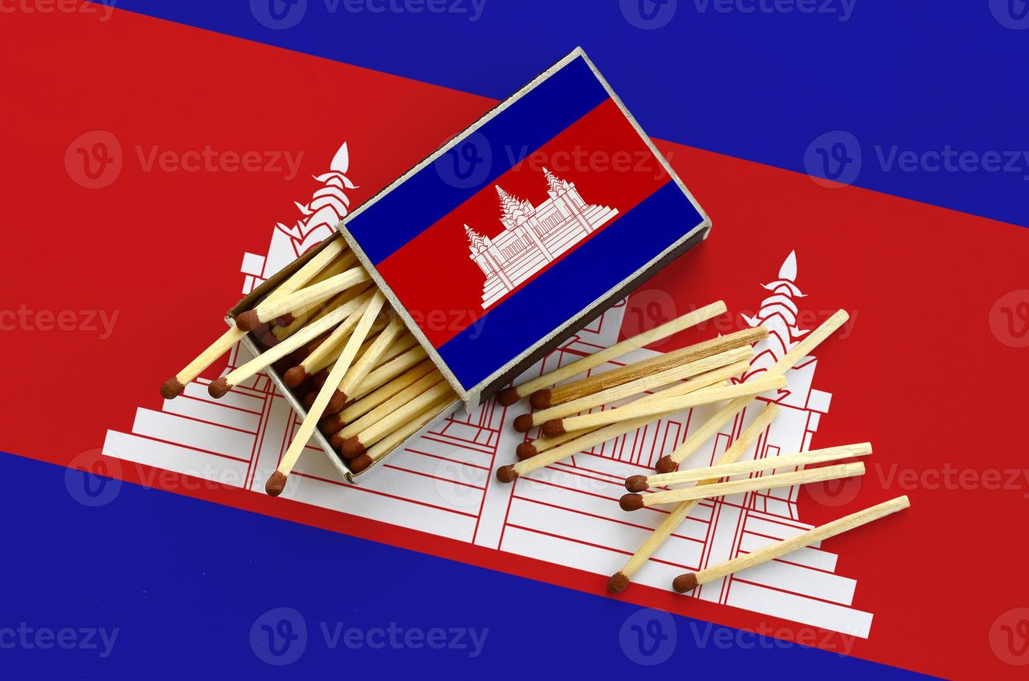 Cambodia flag  is shown on an open matchbox, from which several matches fall and lies on a large flag photo