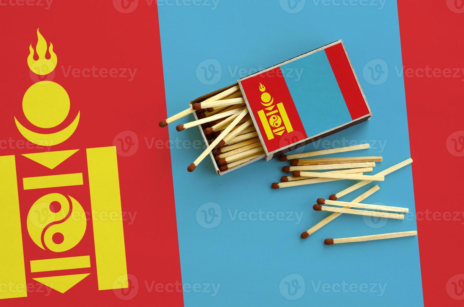 Mongolia flag  is shown on an open matchbox, from which several matches fall and lies on a large flag photo