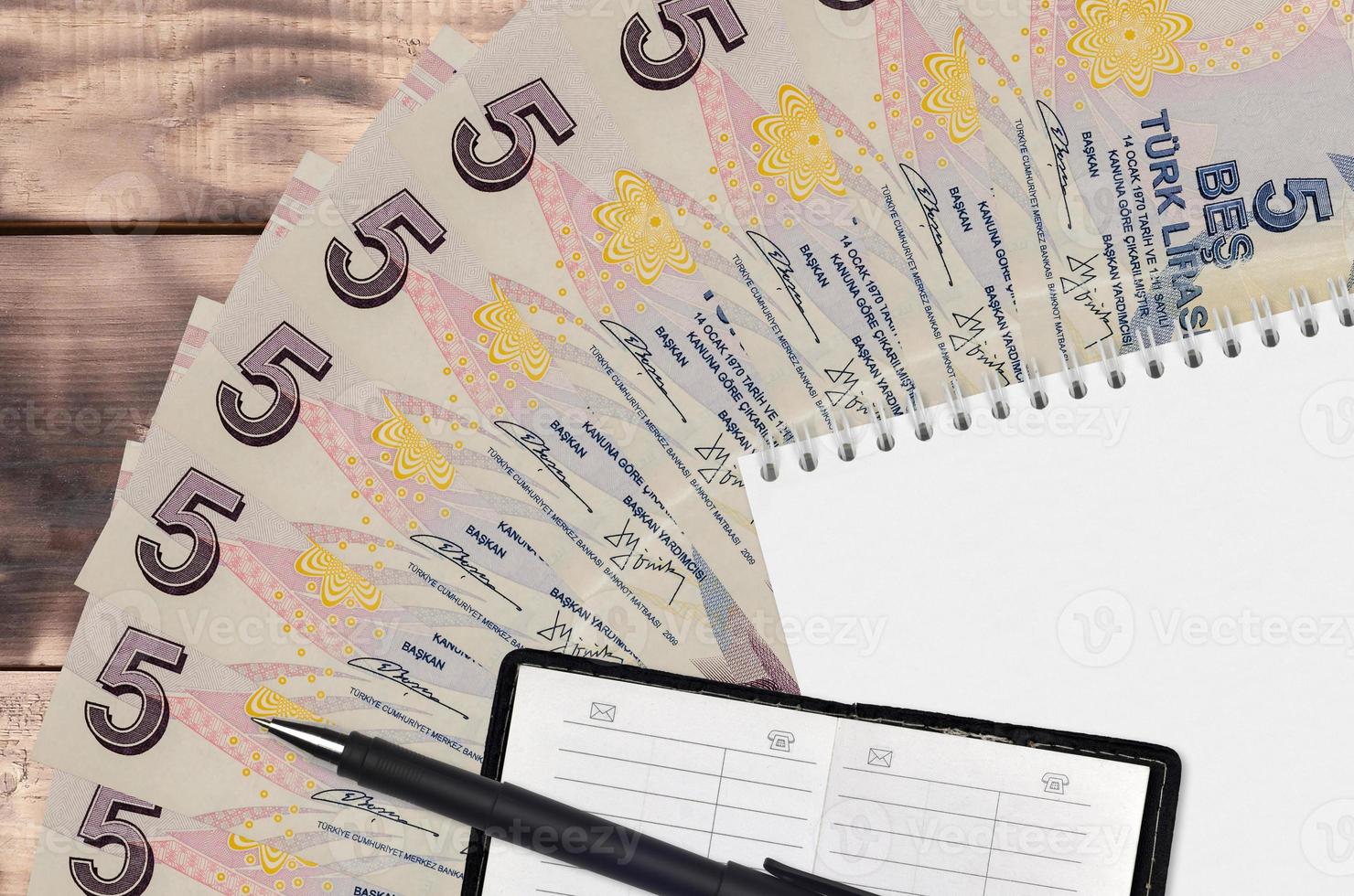 5 Turkish lira bills fan and notepad with contact book and black pen. Concept of financial planning and business strategy photo