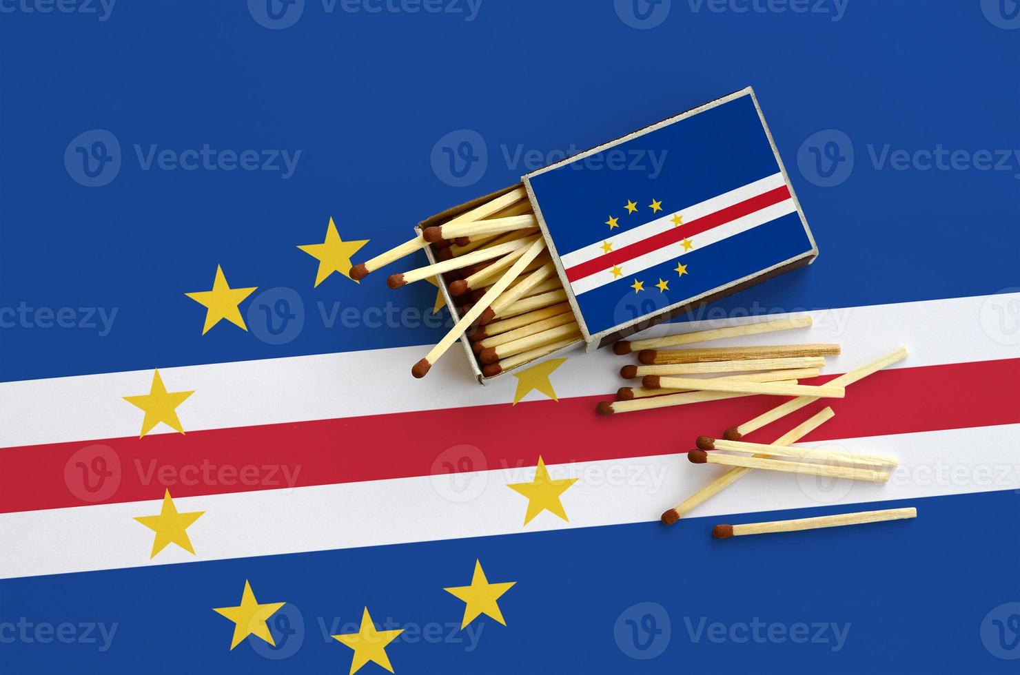 Cabo verde flag  is shown on an open matchbox, from which several matches fall and lies on a large flag photo