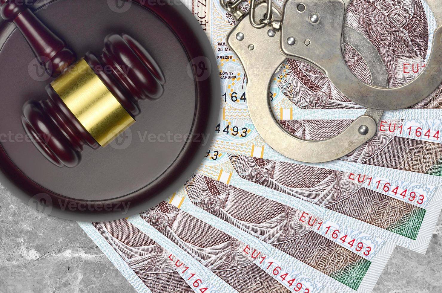 10 Polish zloty bills and judge hammer with police handcuffs on court desk. Concept of judicial trial or bribery. Tax avoidance photo