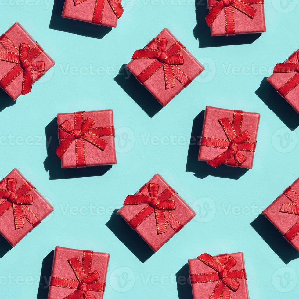 Many small red pink gift boxes on texture background of fashion trendy pastel blue color paper in minimal concept. Abstract pattern photo