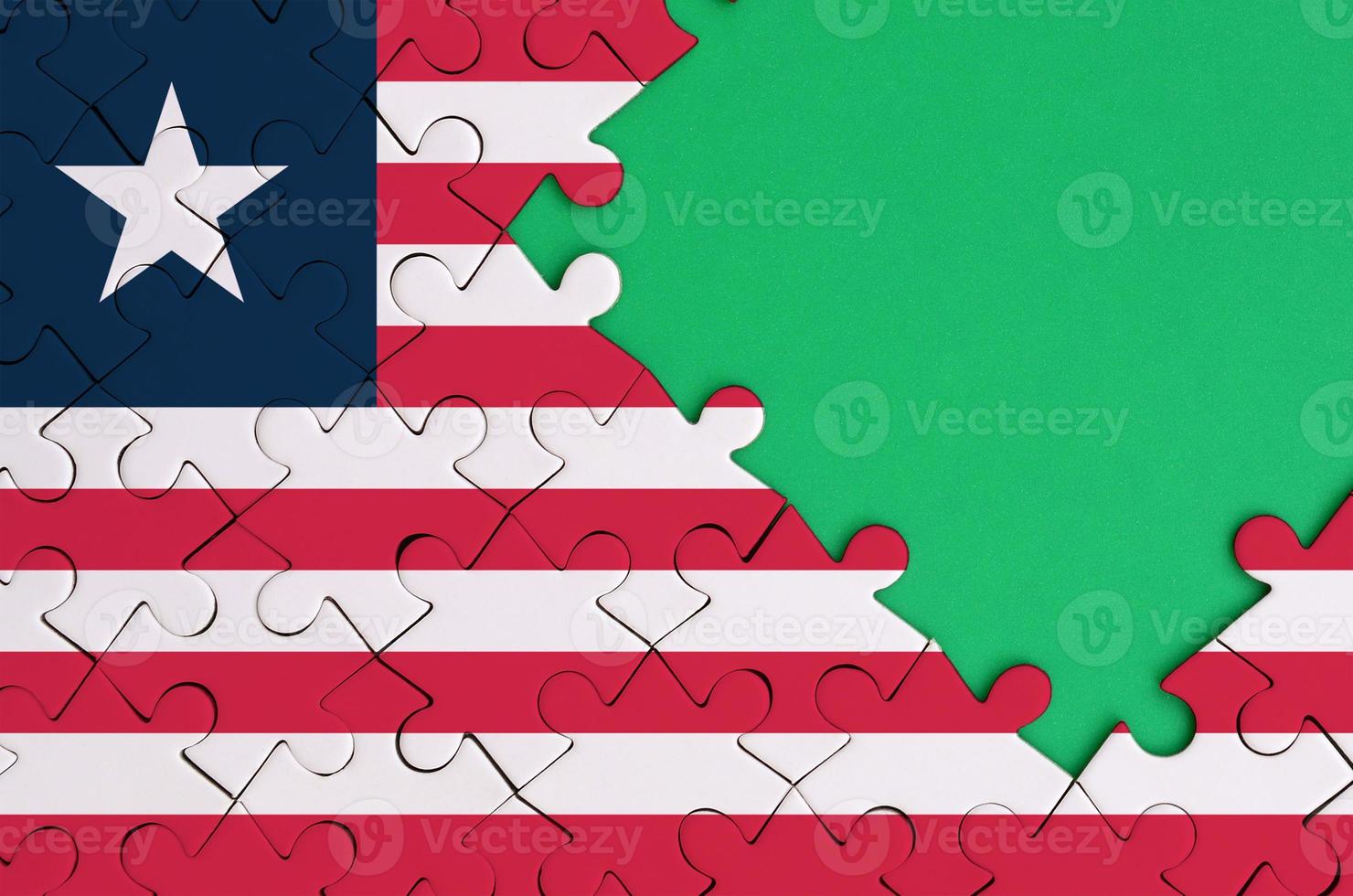 Liberia flag  is depicted on a completed jigsaw puzzle with free green copy space on the right side photo