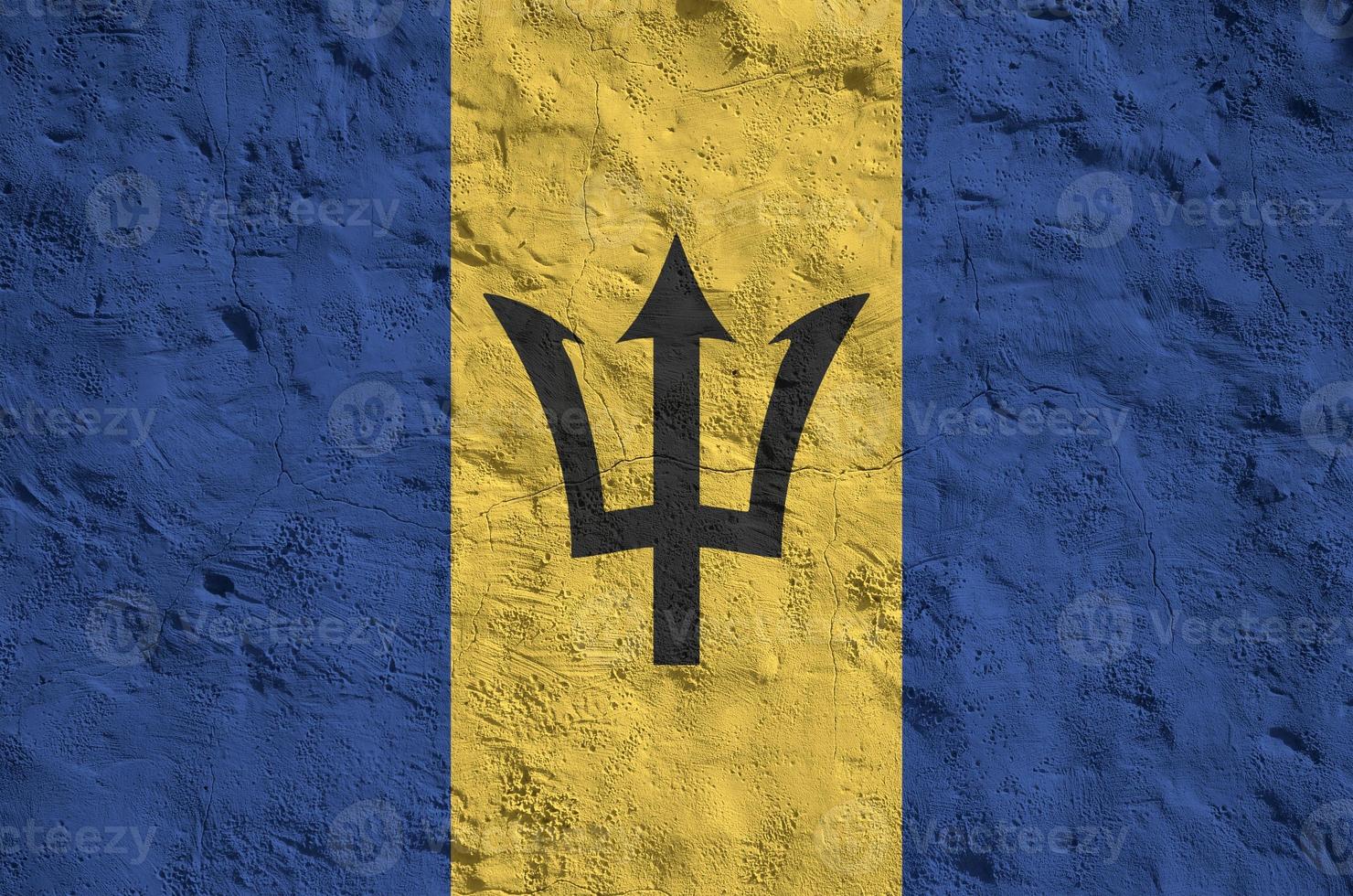 Barbados flag depicted in bright paint colors on old relief plastering wall. Textured banner on rough background photo