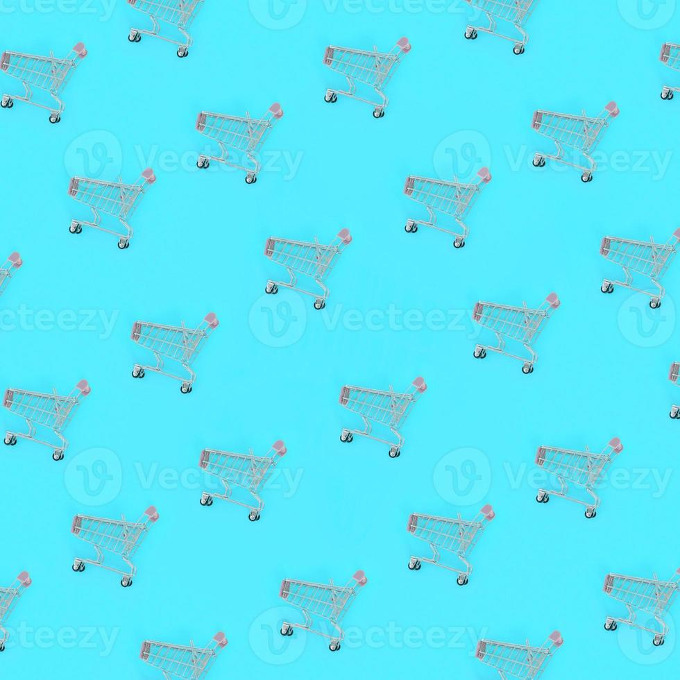 Shopping addiction, shopping lover or shopaholic concept. Many small empty shopping carts perform a pattern on a pastel colored paper background. Flat lay composition, top view photo