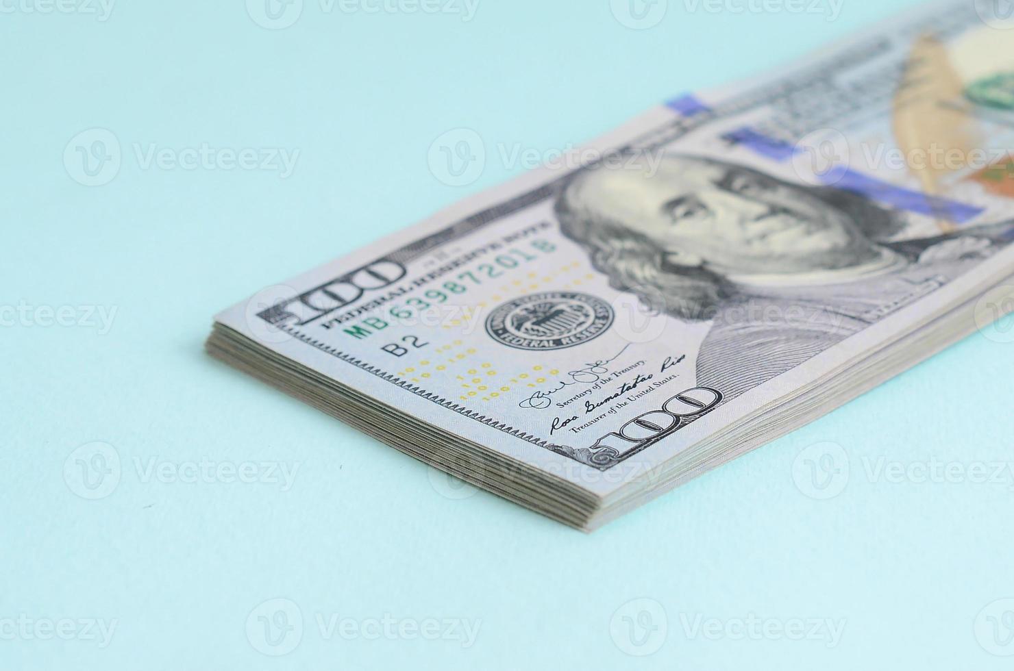 los billetes de dólar estadounidense de un nuevo diseño con una franja azul en el medio se encuentran sobre un fondo azul claro foto