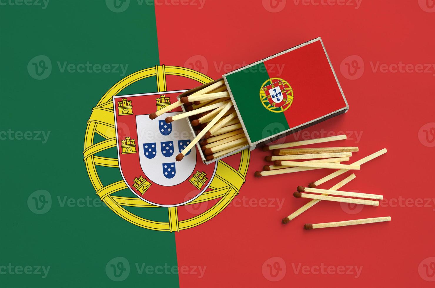 Portugal flag  is shown on an open matchbox, from which several matches fall and lies on a large flag photo