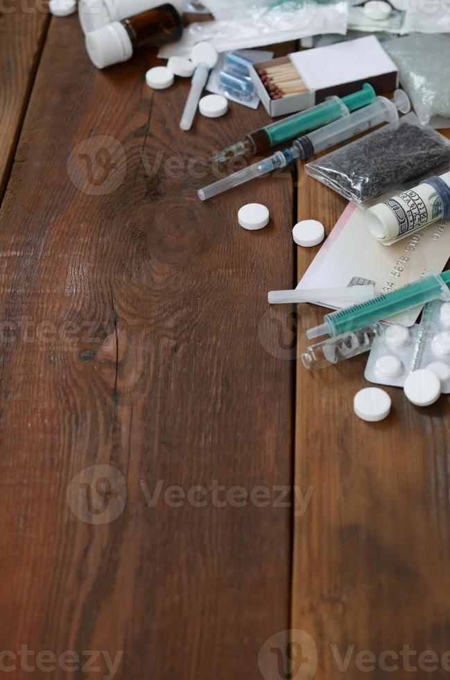 A lot of narcotic substances and devices for the preparation of drugs lie on an old wooden table photo