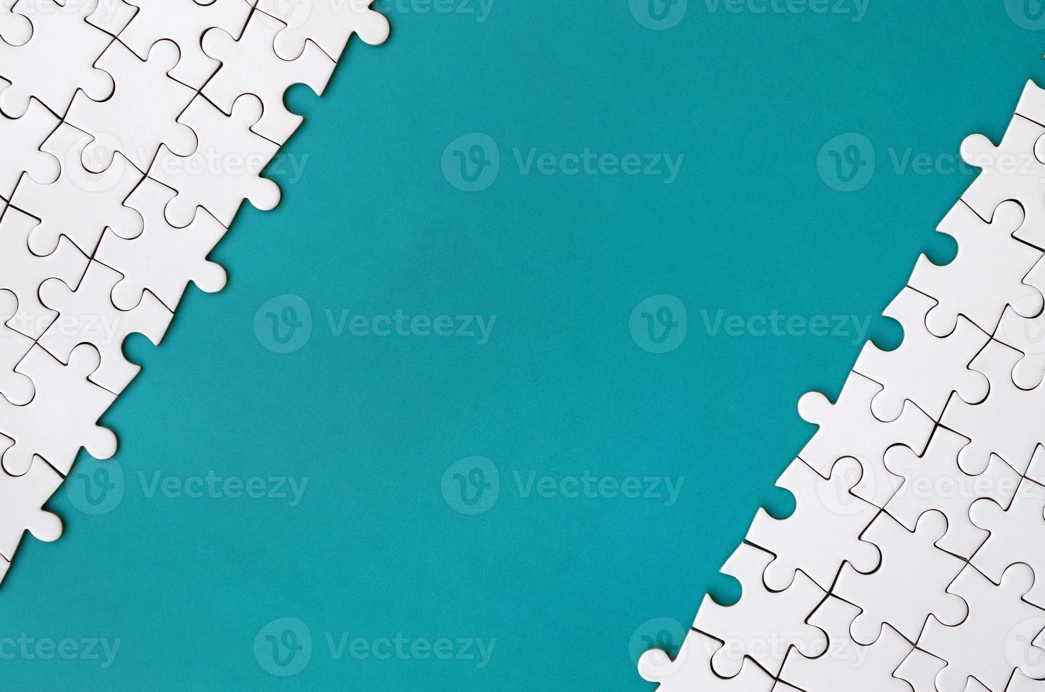 Fragment of a folded white jigsaw puzzle on the background of a blue plastic surface. Texture photo with copy space for text