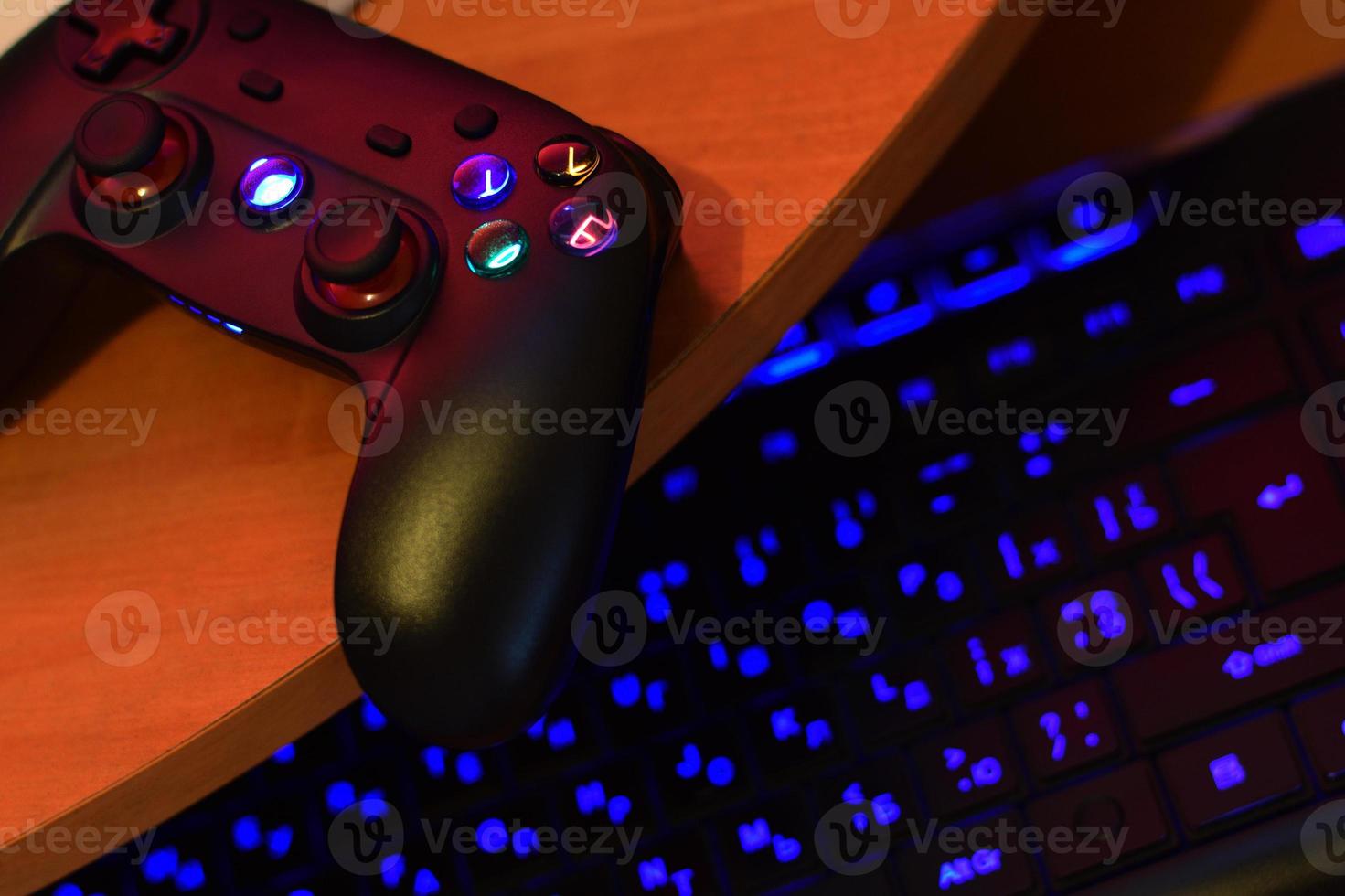 Modern gamepad lies with pc keyboard on table in dark playroom scene. Cooperative teamplay concept photo