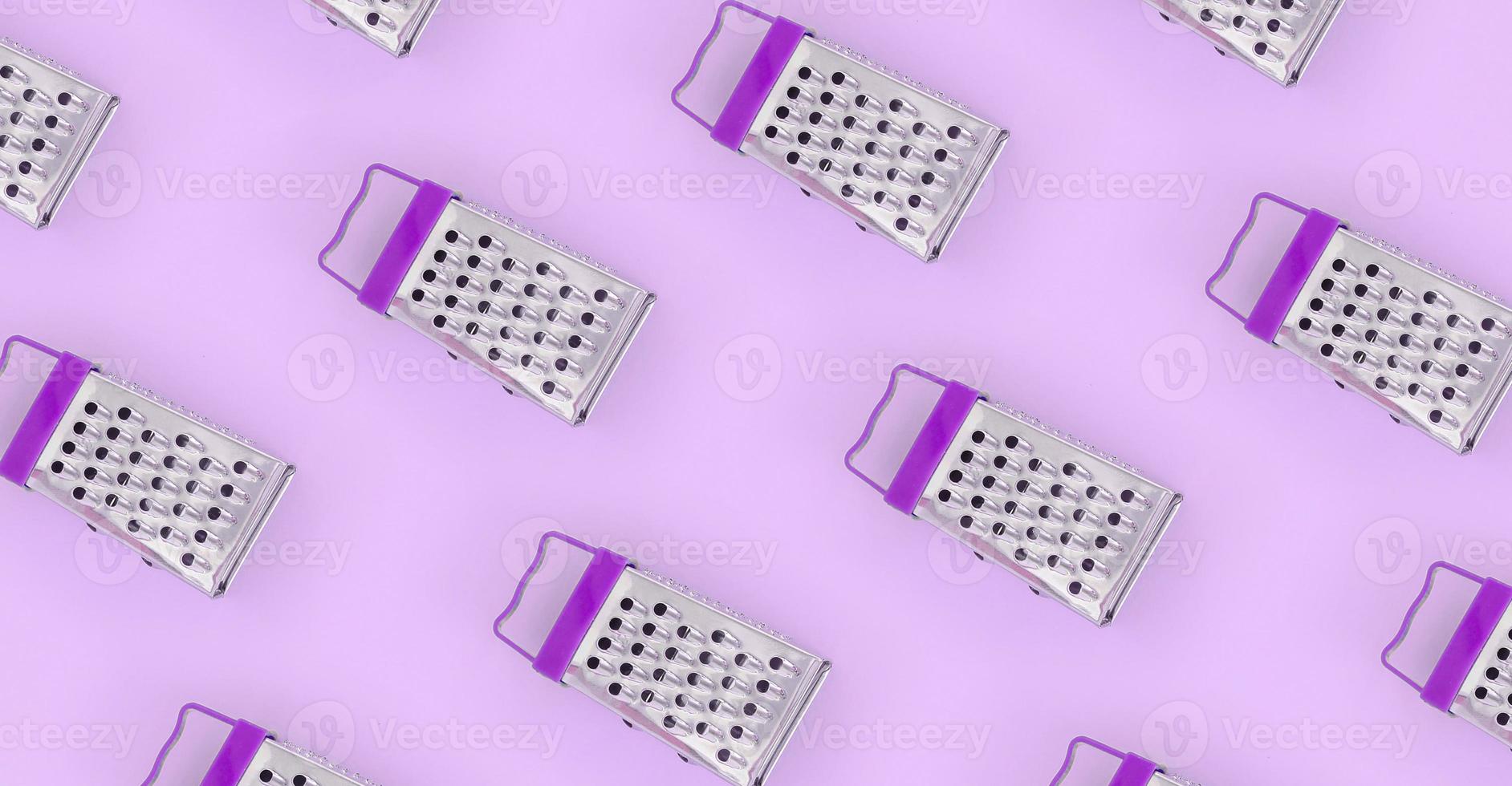 Small stainless steel graters lies on a pastel colored paper. Kitchen accessories. Tools for cooking. Flat lay top view photo