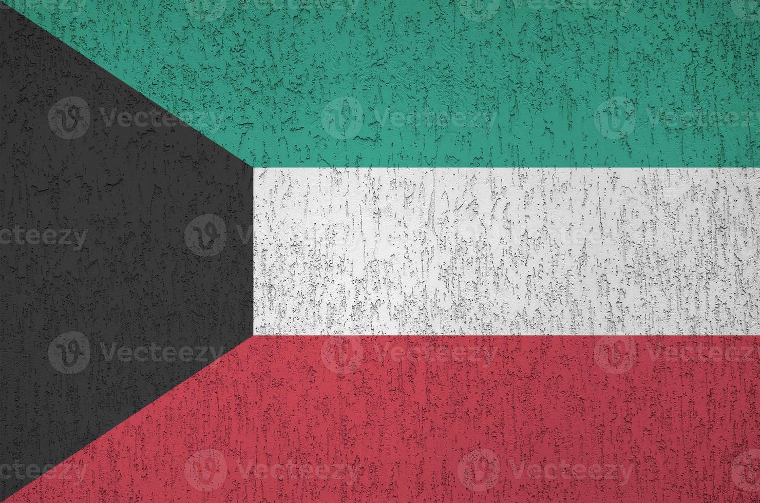 Kuwait flag depicted in bright paint colors on old relief plastering wall. Textured banner on rough background photo