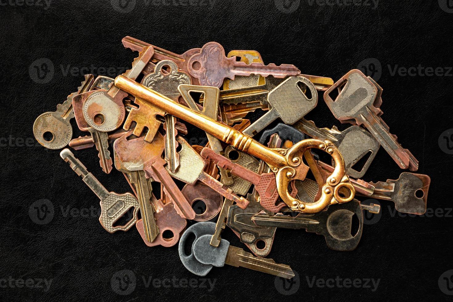 Golden master key in the center of the image. with pattern many keys on black floor photo