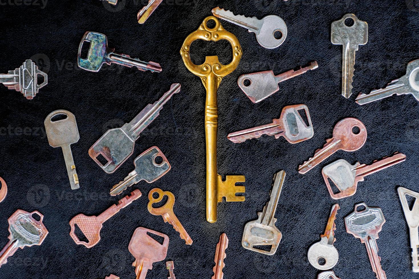 Golden master key in the center of the image. with pattern many keys on black floor photo