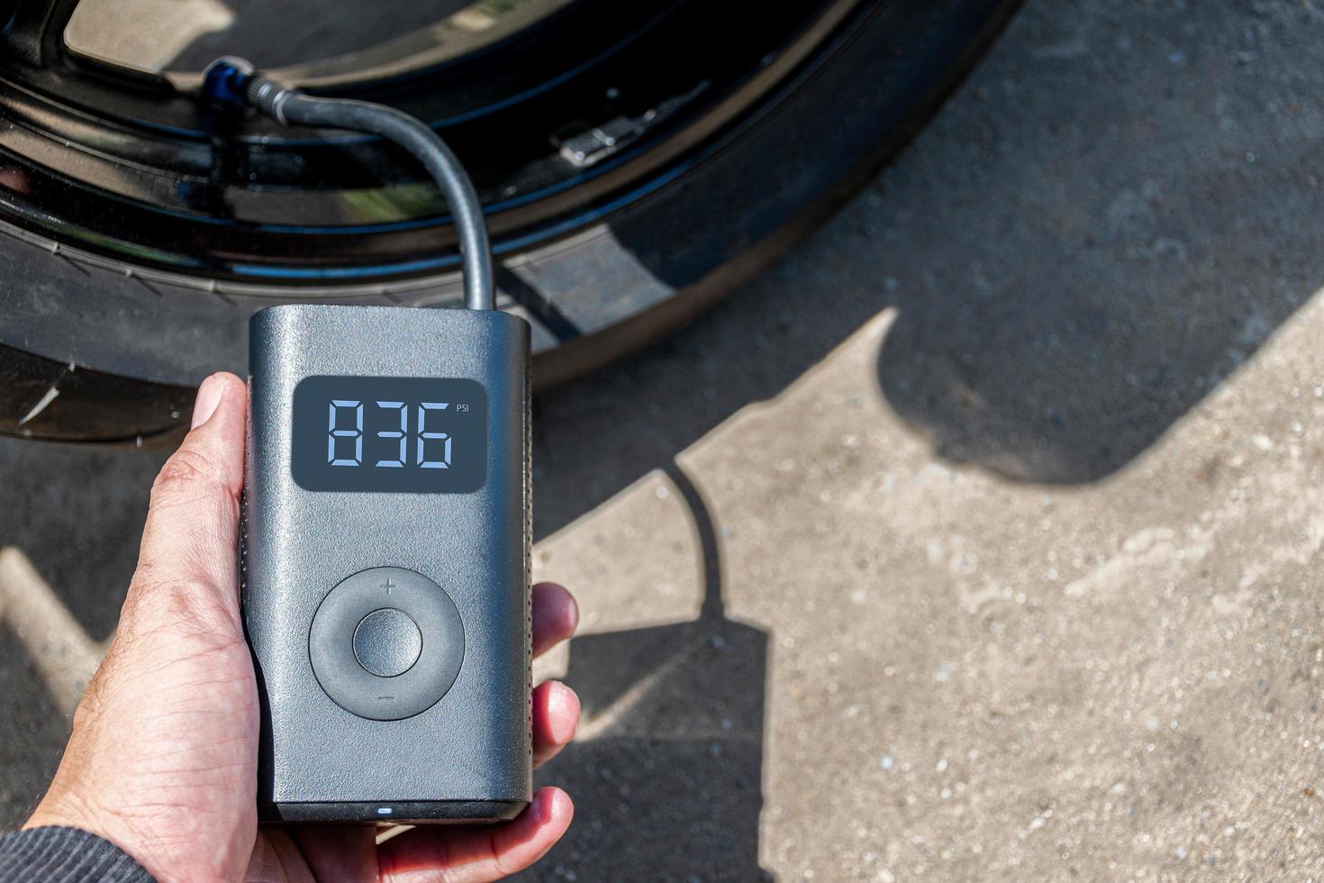 Hand holding a portable inflator is inflating a motorcycle tire. photo