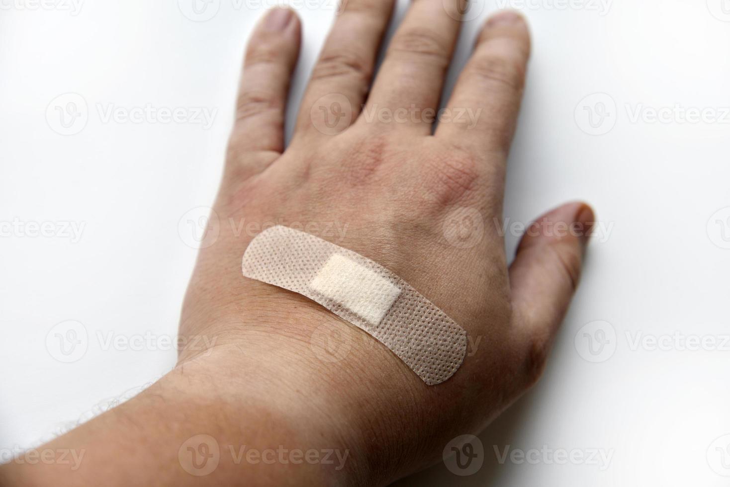 A medical patch on a man's arm on a white background. A yellow patch on the wound on his arm. photo