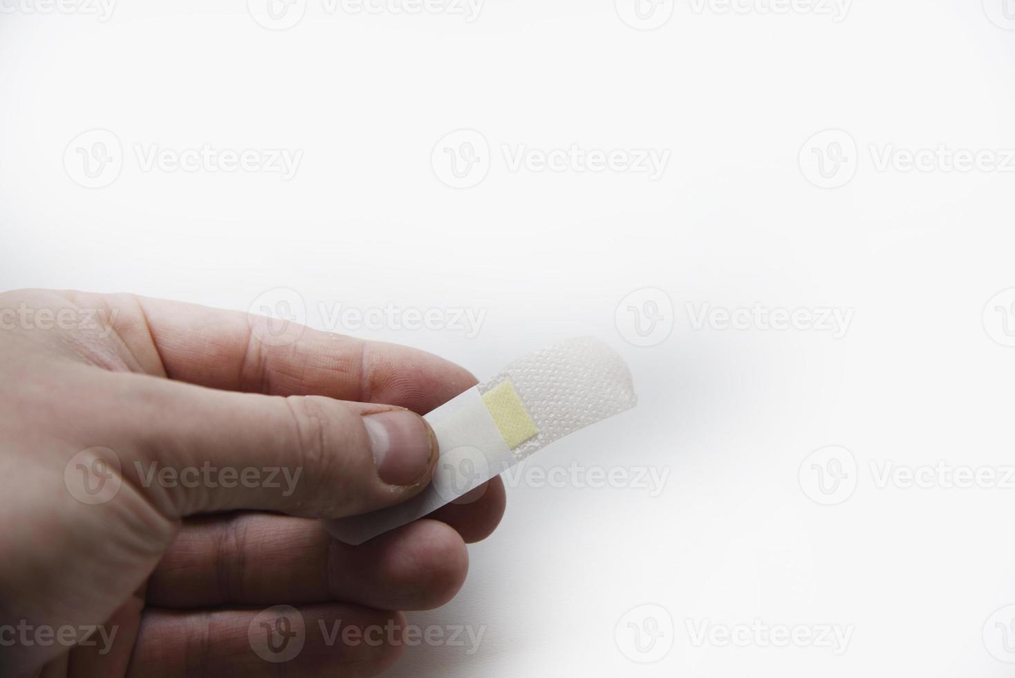 A medical patch on a man's arm on a white background. A yellow patch on the wound on his arm. photo