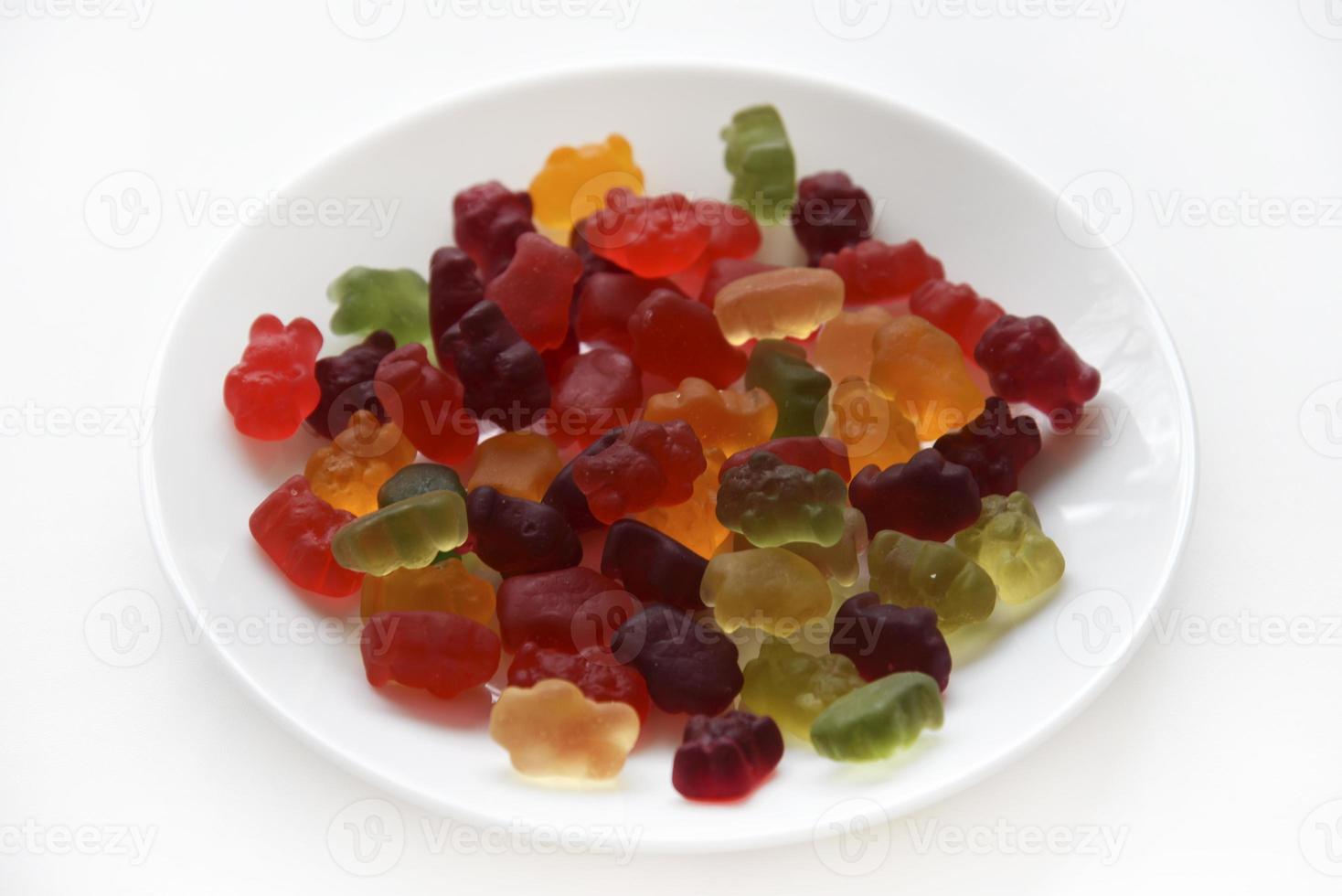 Marmalade gelatin sweet bears on a white plate. Delicious marmalades on a white background. photo