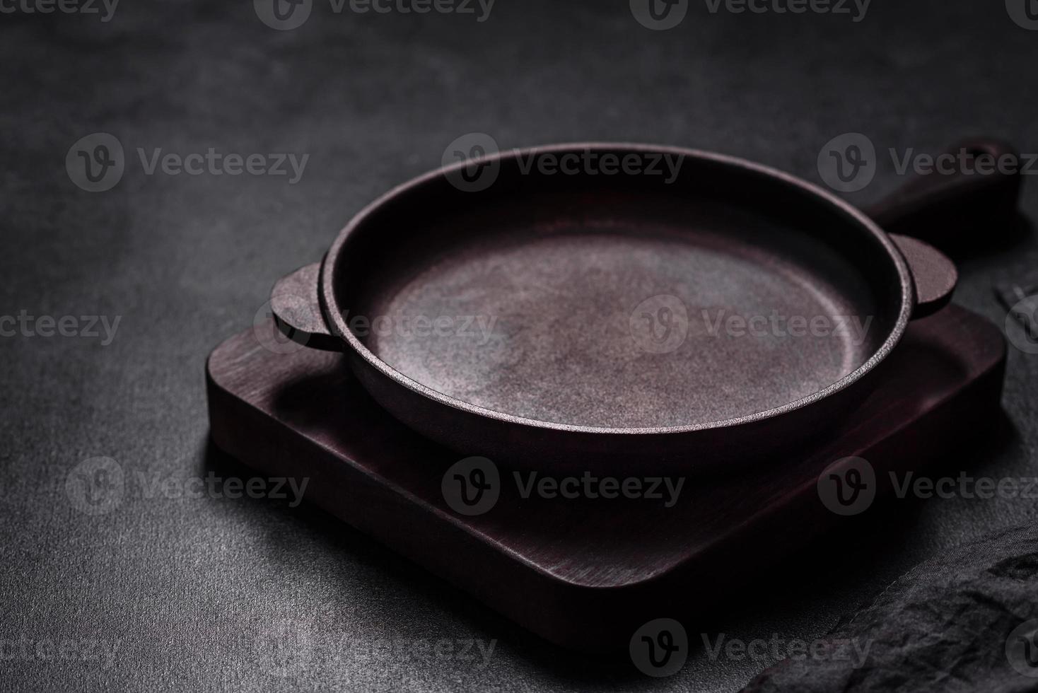 Brown iron empty pan with kitchen utensils on a dark concrete background photo